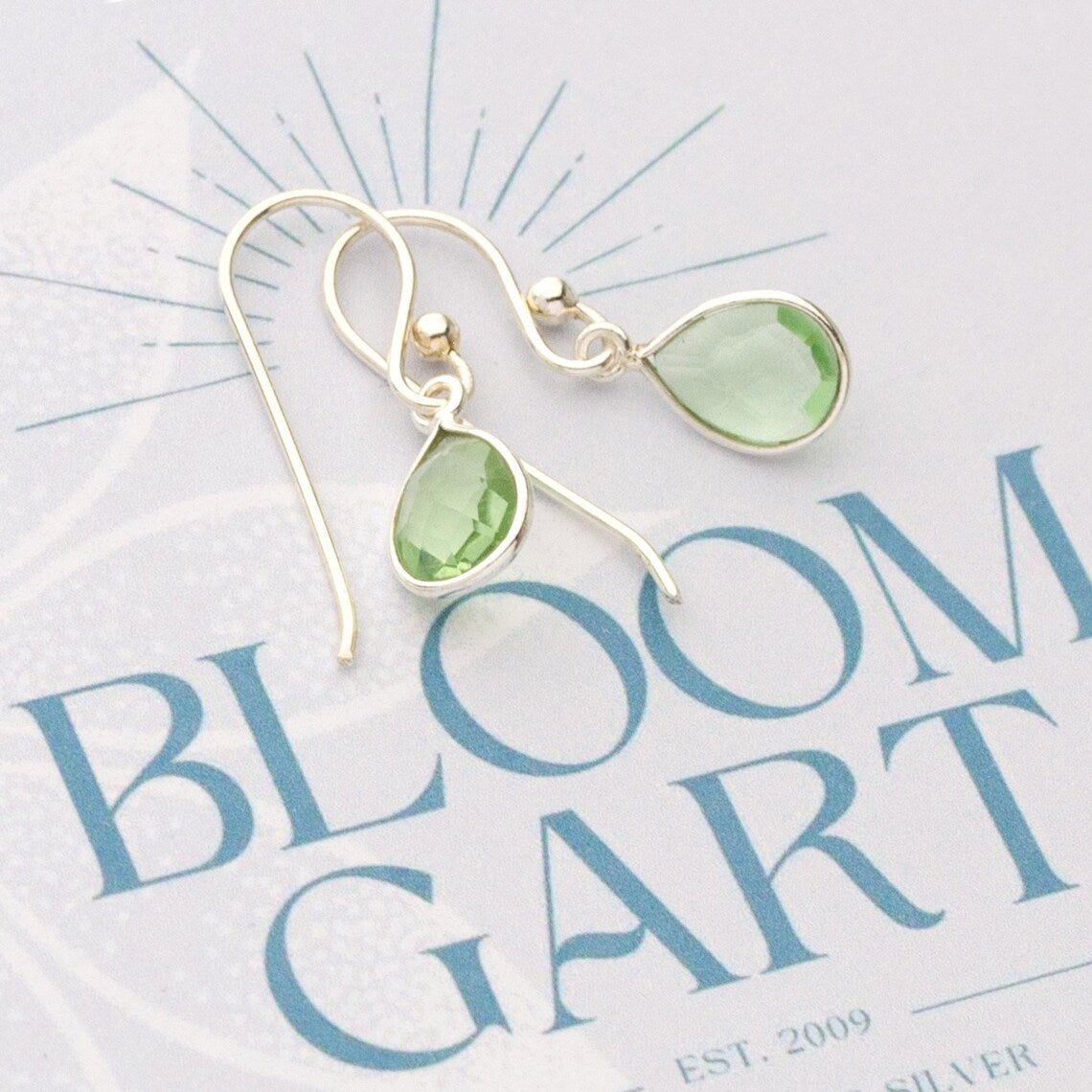 Zierliche Tropfen-Ohrringe mit grünem Amethyst und 925 Sterling Silber Fassung auf einer Bloomgart Geschenkkarte geschenkbereit befestigt.