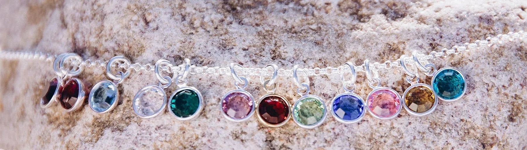 Zwölf farbige Monatssteine im Sonnenschein auf einem Felsen fotografiert.