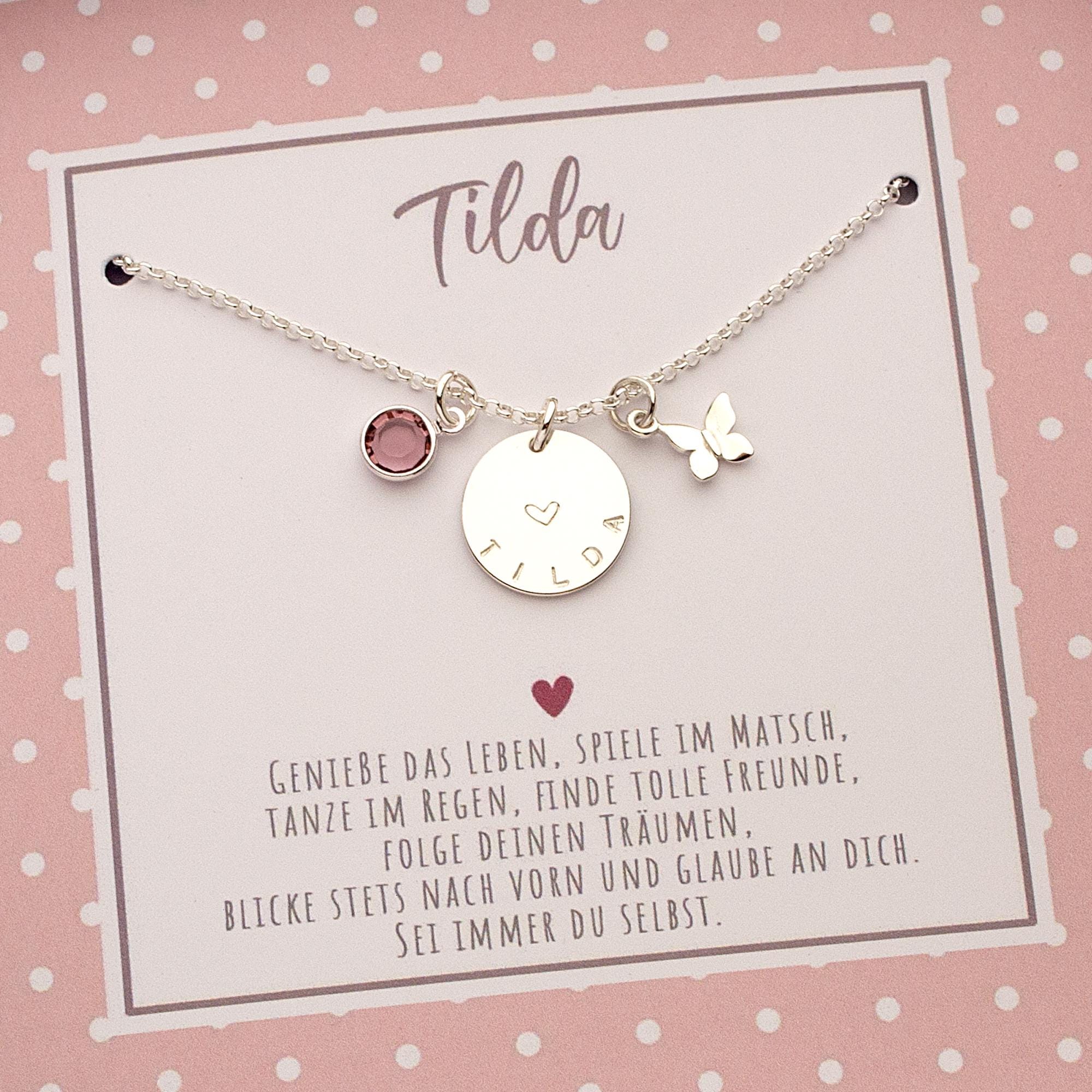 Innenansicht der rosa Geschenkbox mit persönlichem Spruch, Namen und weißen Pünktchen. Unterhalb des Namens 'Tilda' ist eine Silberkette mit drei Anhängern montiert.