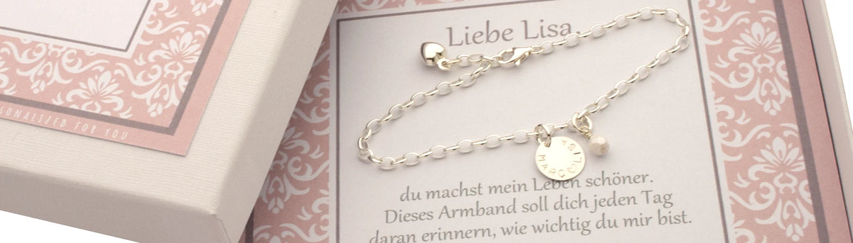 Detailansicht einer weiß-rosa Geschenkbox mit personalisiertem Silberarmband mit Gravur "MARC ♡ LISA" und persönlicher Liebesbotschaft "Liebe Lisa, du machst mein Leben schöner. Dieses Armband soll dich jeden Tag daran erinnern, wie wichtig du mir bist. Wunderschönes Geschenk zu Verlobung, Jahrestag oder Hochzeitstag von Bloomgart.