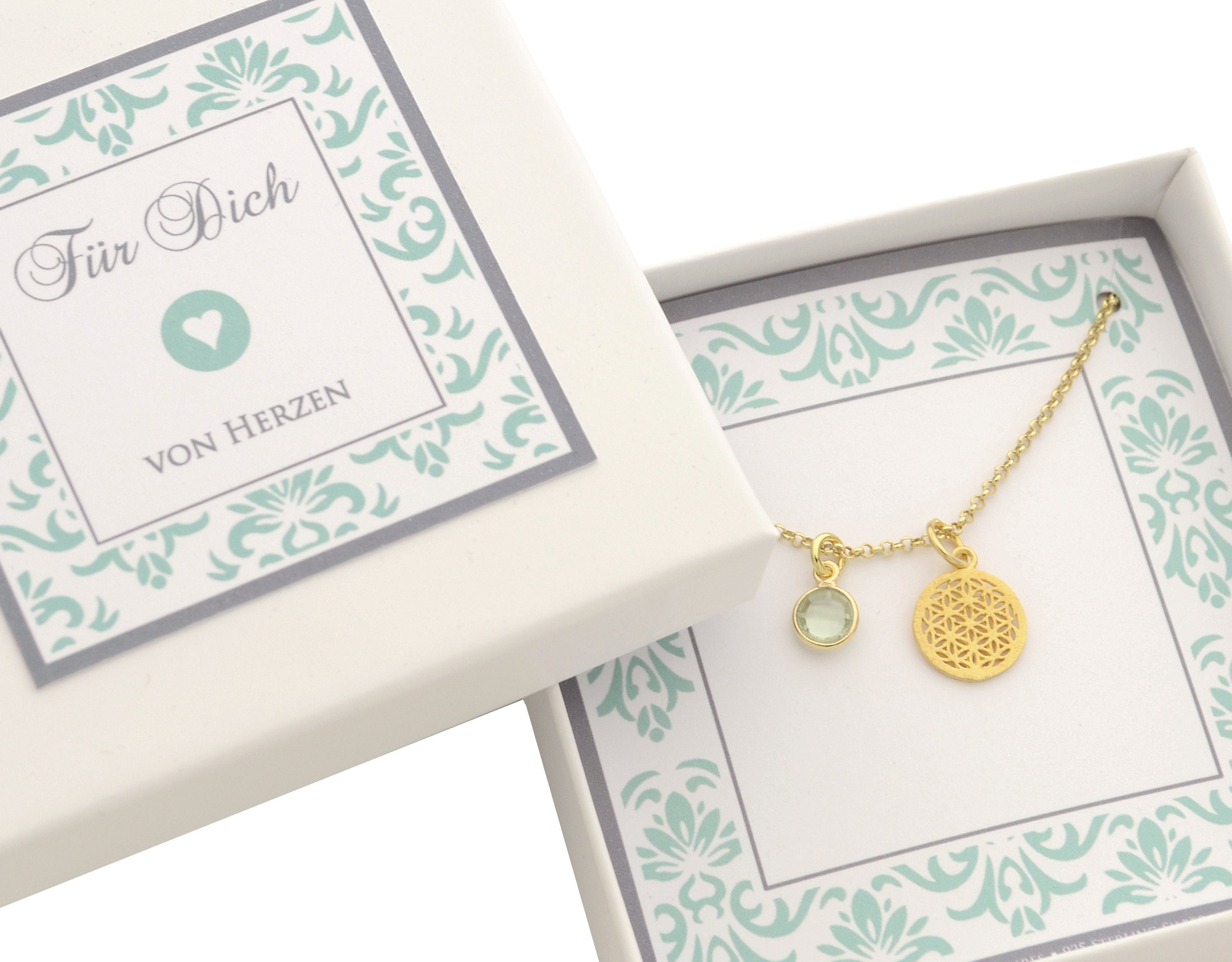 Vergoldete Kette mit Lebensblume-Anhänger und einem grünen Amethyst-Edelstein, präsentiert in einer kleinen Geschenkbox mit der Aufschrift "Für Dich von Herzen".