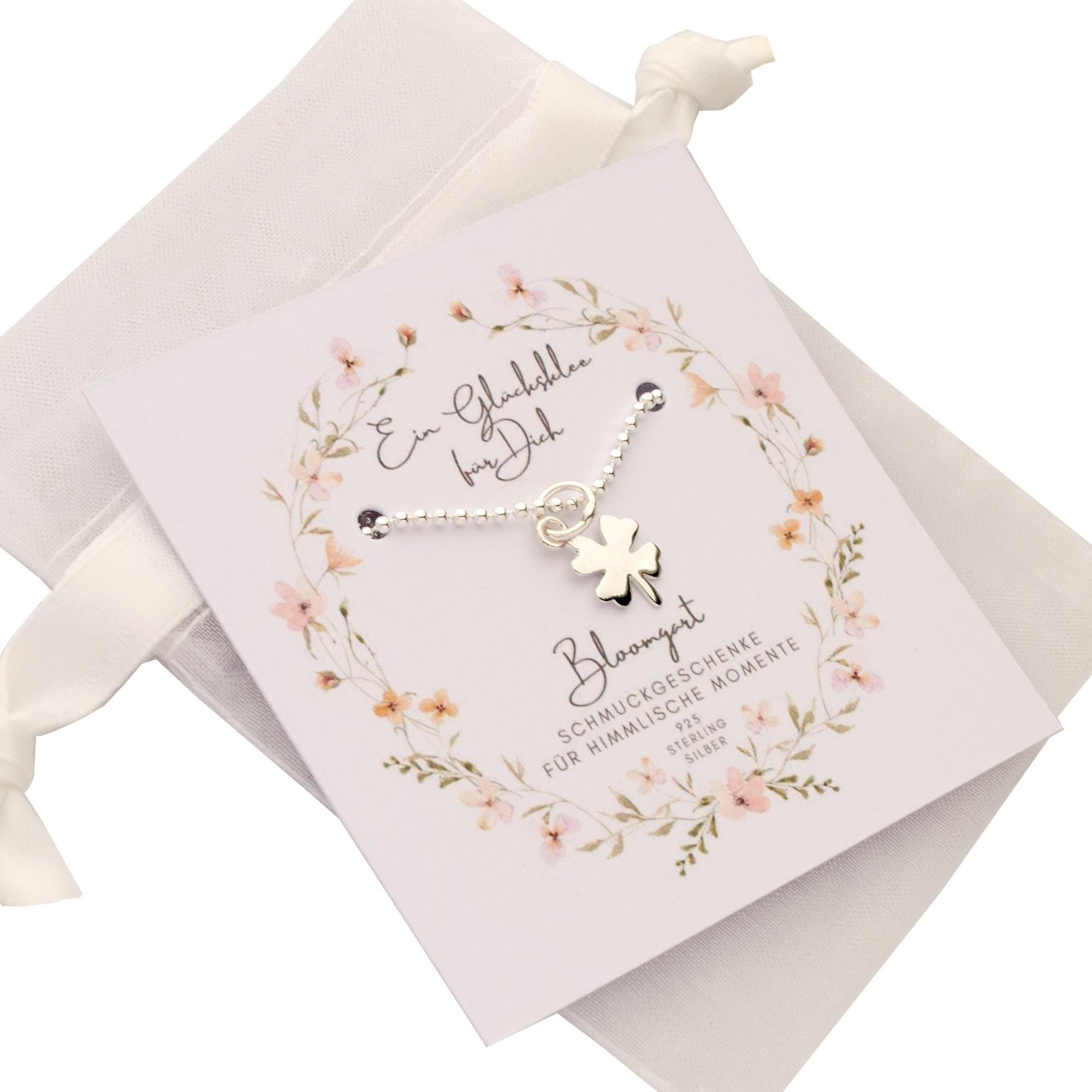 Ein Kleeblatt Schmuckanhänger an einer zierlichen Halskette aus 925 Silber als kleines Geschenk für die Schultüte. Süß verpackt auf einer Bloomgart-Karte im weißen Organza-Säckchen.