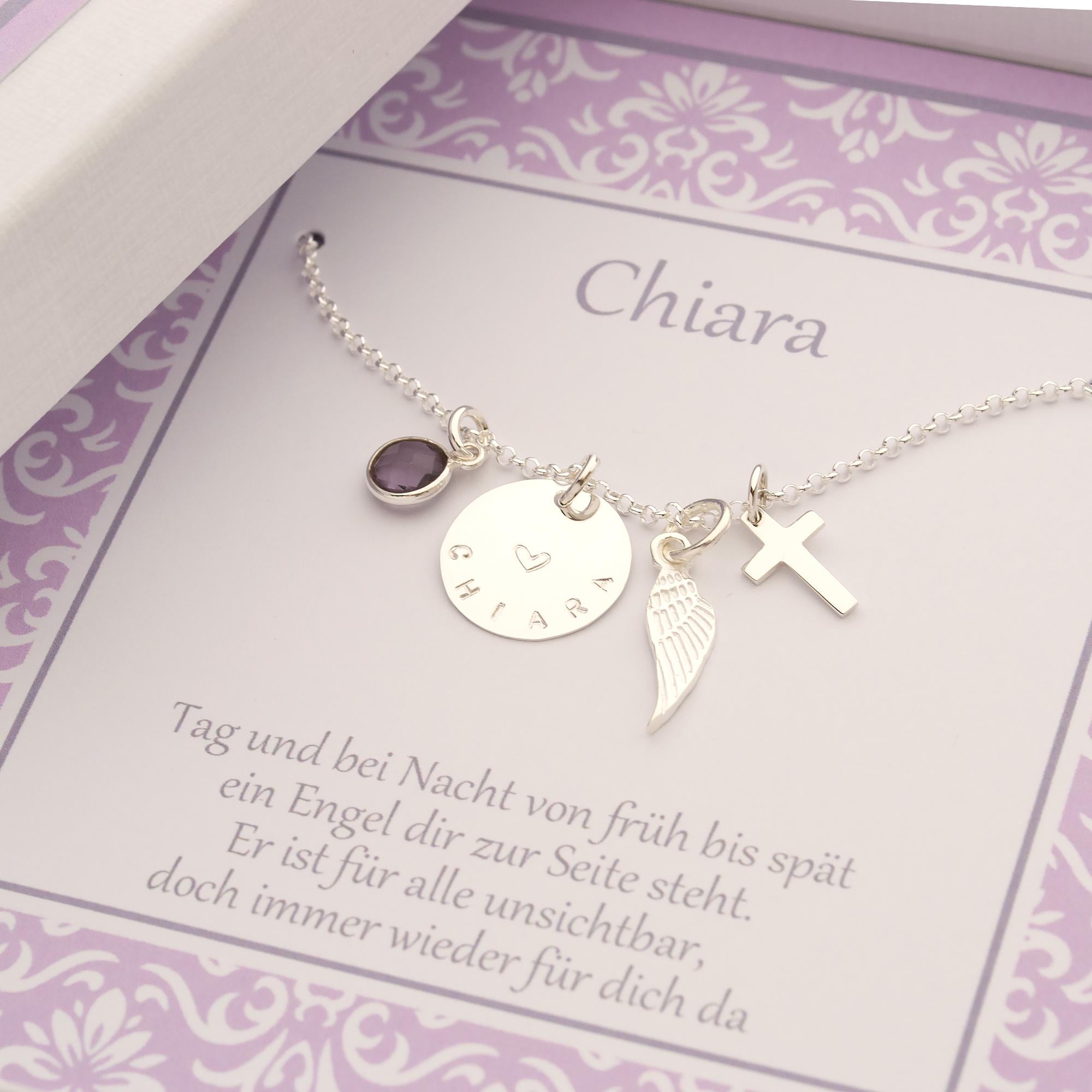 Detailansicht der Kettenanhänger: Amethyst, Namensplättchen, Engelsflügel und Kreuz. Hier in einer personalisierten geschenkbox für 'Chiara'.