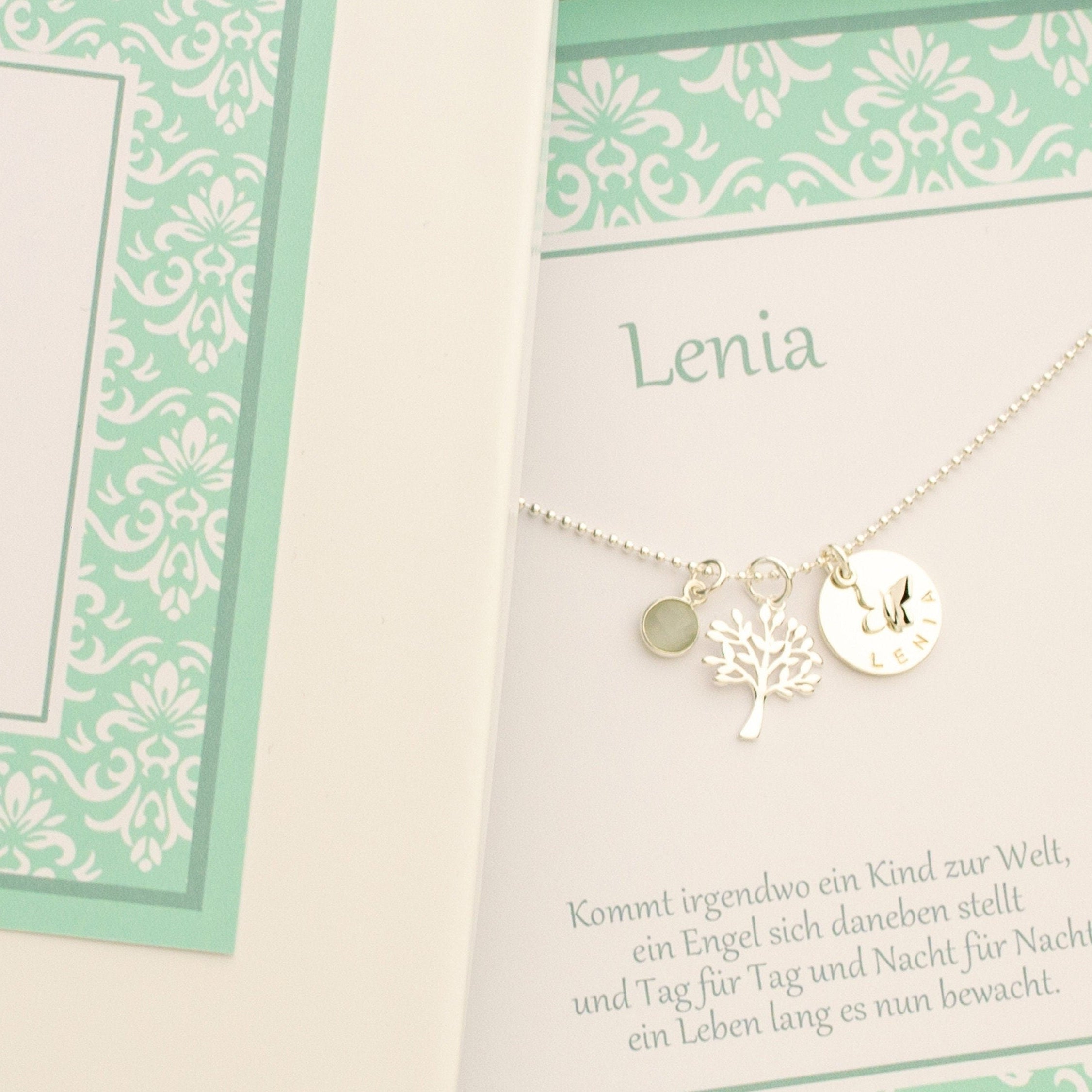 Detailansicht einer Kugelkette aus 925 Silber mit Namenstaler, hier 'LENIA'. Schmetterling, Lebensbaum und Mondstein in einer mintfarbigen Ornament-Geschenkbox.