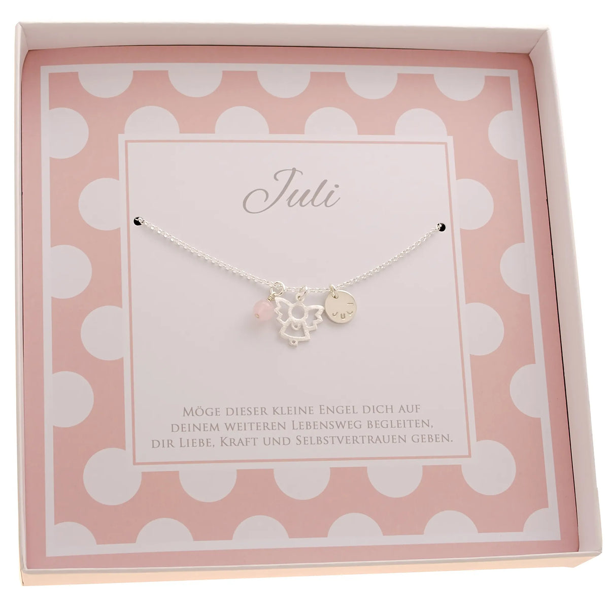 Innenansicht einer rosa-weiß gepunkteten Geschenkbox mit Namenskette mit handgestempelter Gravur auf einem Silbertaler, einem Schutzengel und einer Rosenquarz-Kugel