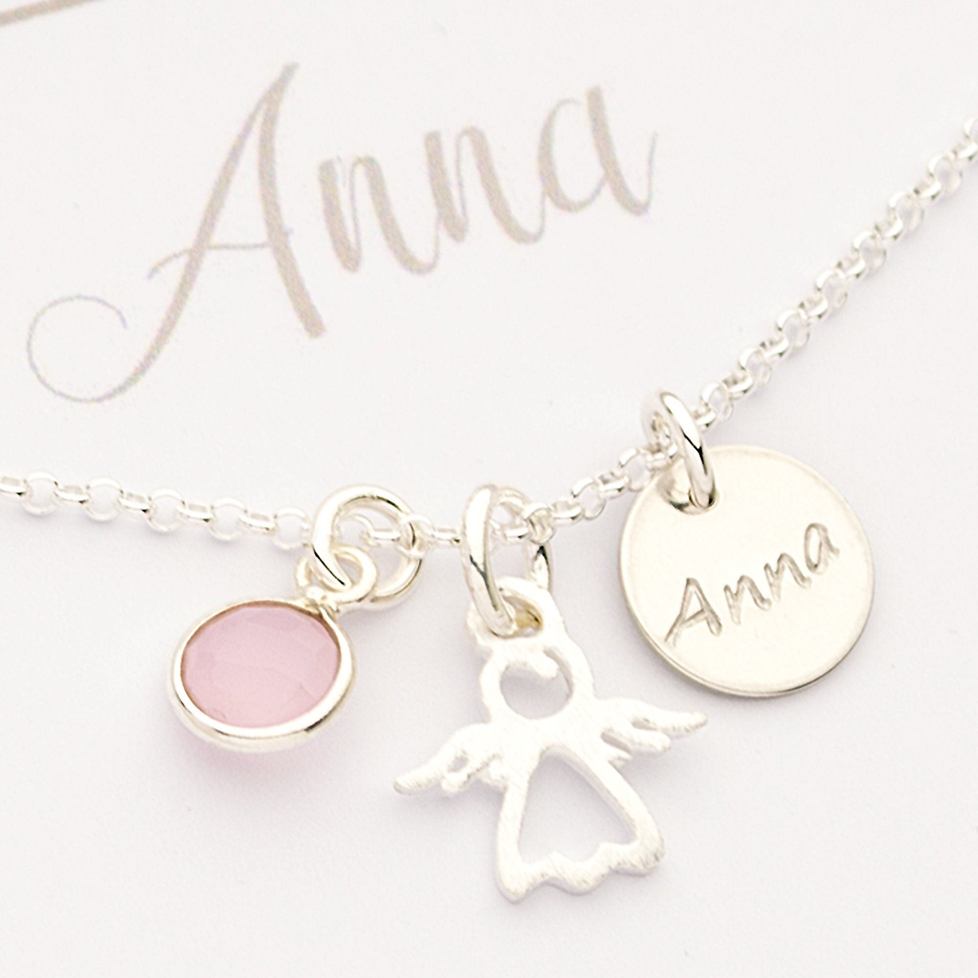 Nahansicht einer filigranen Silberkette, personalisiert für 'Anna' mit Namenstaler, Engel und Rüsenquarz.