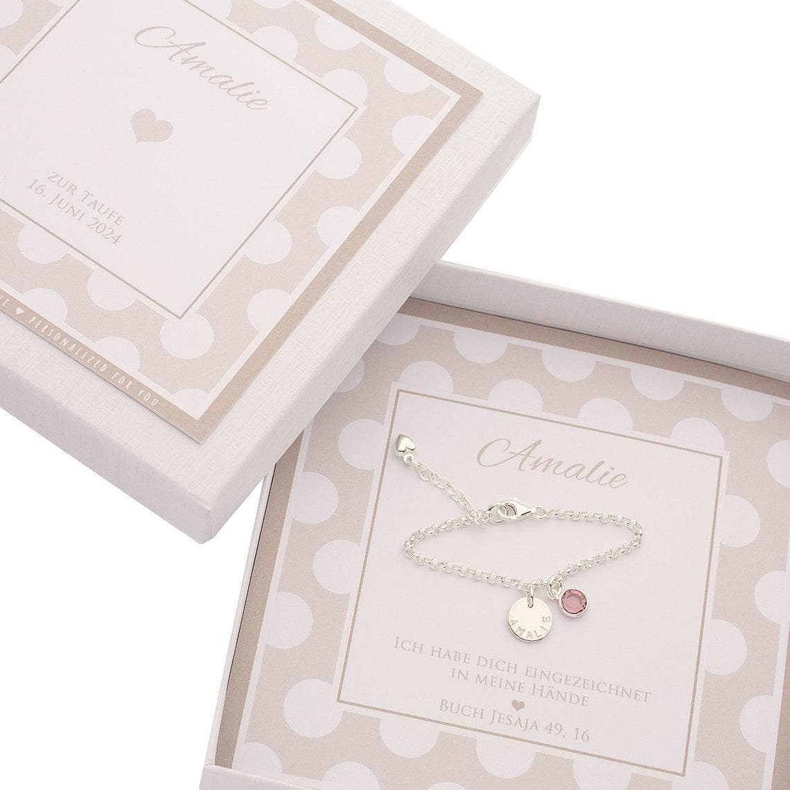 Ein personalisiertes Armband mit Namen-Gravur "AMELIE" aus 925 Sterling Silber und Geburtsstein in einer weiß-beigen Geschenkbox zur Taufe.