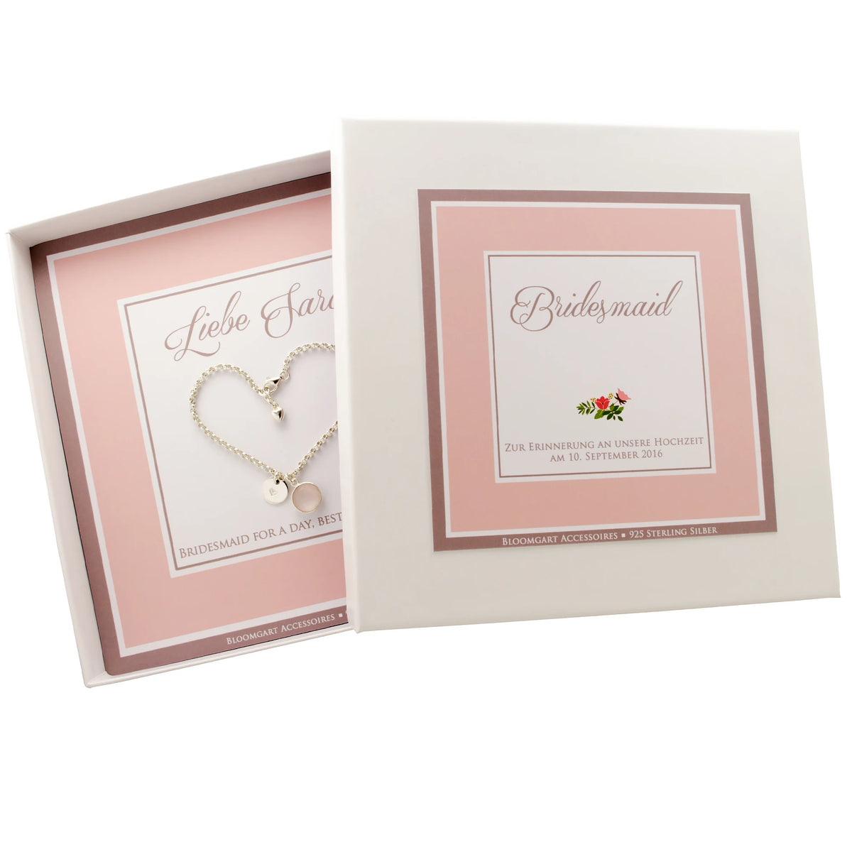 Ein personalisiertes Hochzeitsgeschenk für die Trauzeugin in rosa-weißer Geschenkbox mit Silberarmband. Das Armband ziert ein Edelstein in Wunschfarbe, hier ein rosa Rosenquarz und ein Gravurtaler mit handgestempeltem Herz.