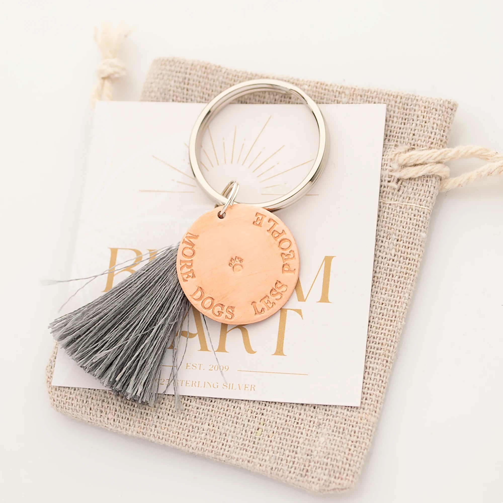 Individueller Schlüsselanhänger 'MORE DOGS LESS PEOPLE' mit Wunschgravur, von Hand gestempelt, grauer Quaste und Leinen-Säckchen von Bloomgart