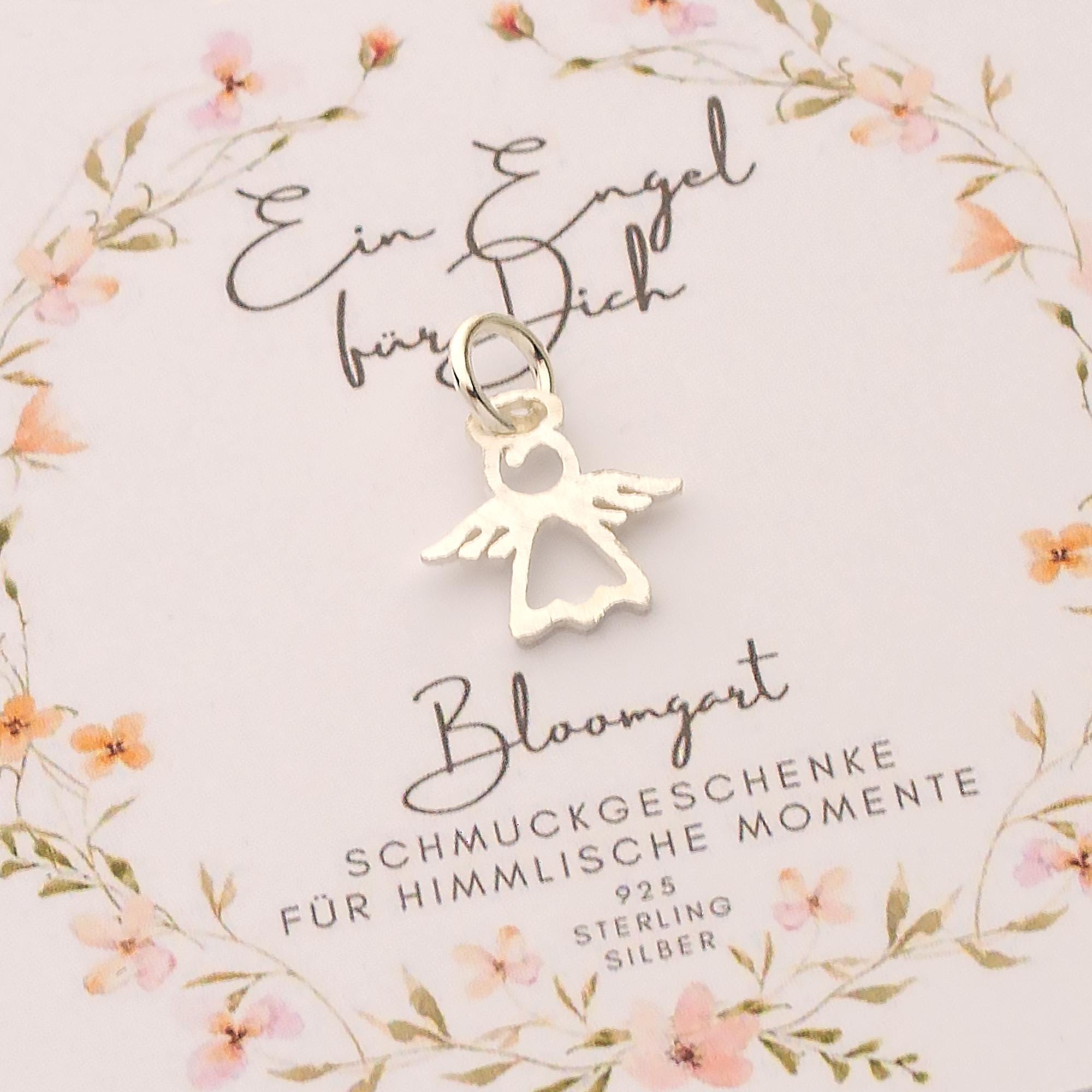 Filigraner Glücksbringer in Form eines 925 Sterling Silber Engels als Einzelanhänger auf einer mit Blumen verzierten Karte.