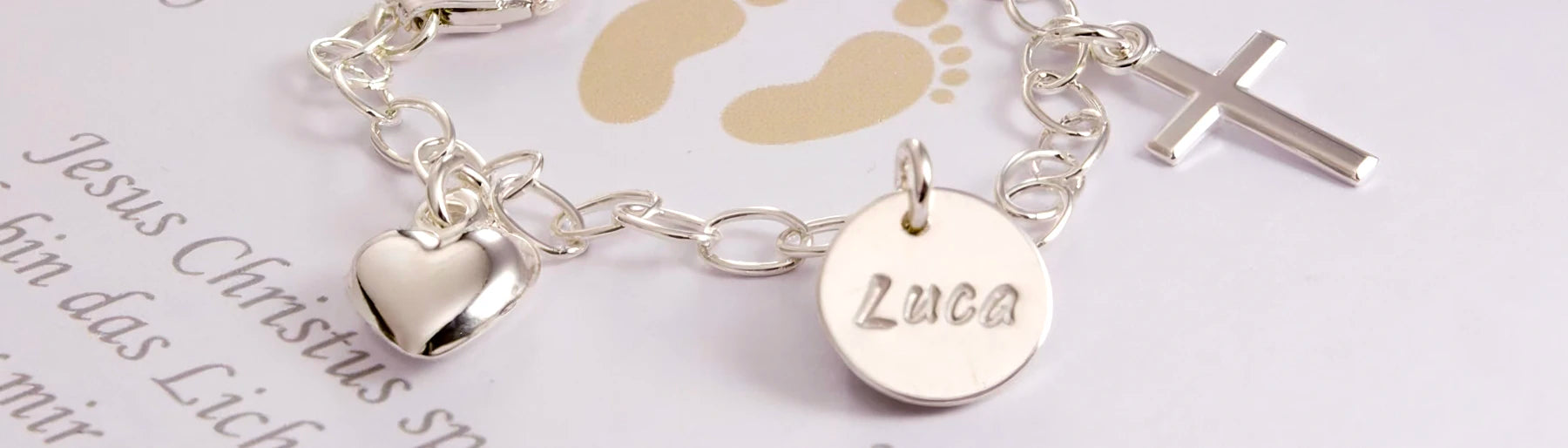 Detailaufnahme eines Taufarmbandes mit Namengravur, Herz und Kreuz aus 925 Sterling Silber.