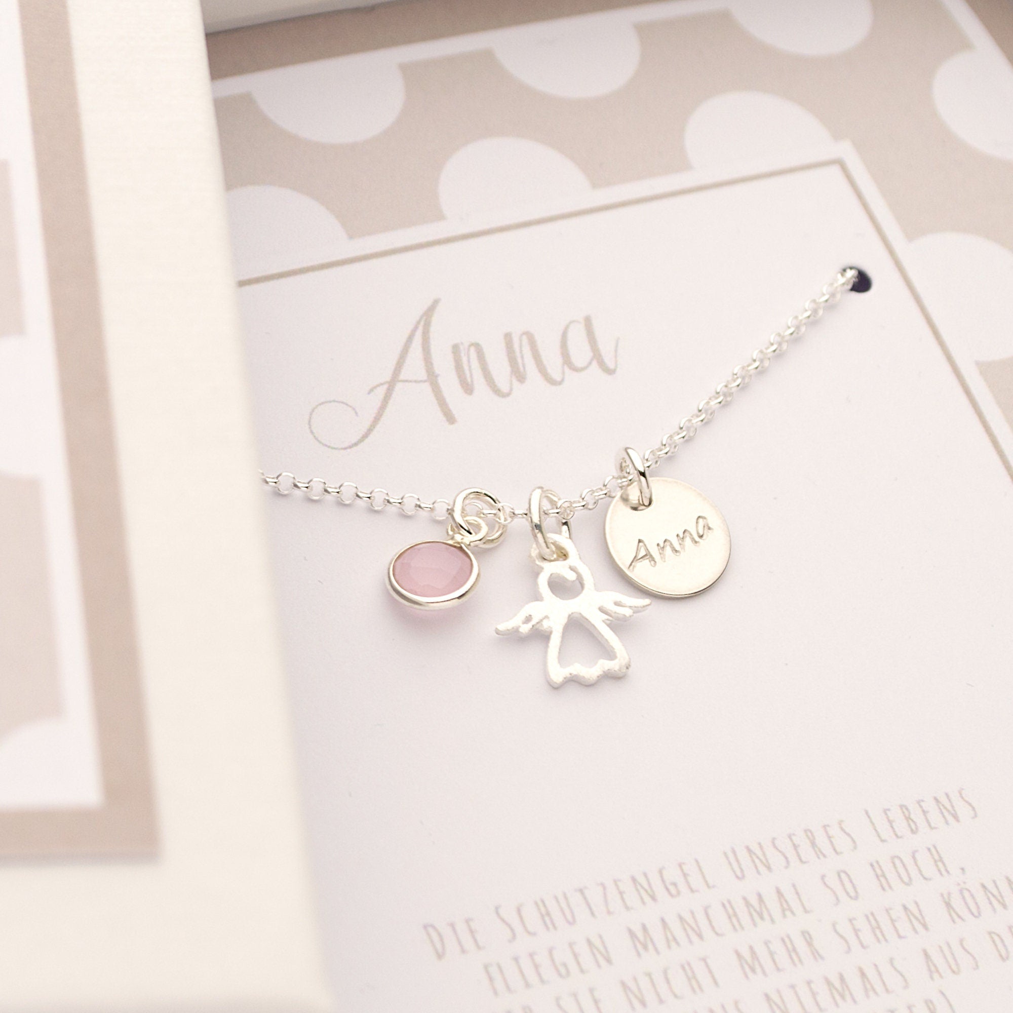 Einblick in eine personalisierte Geschenkbox mit beige-weißem Punktemuster und Schutzengel-Spruch: 'Die Schutzengel unseres Lebens fliegen manchmal so hoch, dass wir sie nicht mehr sehen können ...'