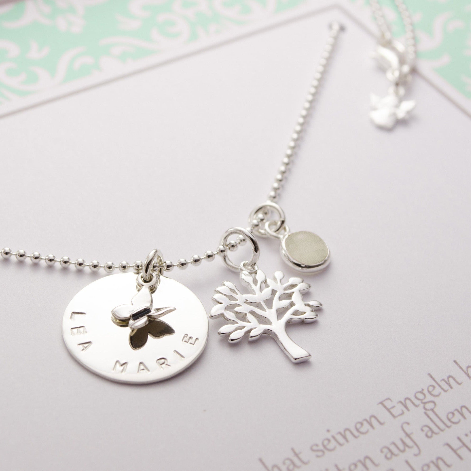 Taufkette aus 925 Sterling Silber mit Lebensbaum und Namensplättchen, präsentiert in einer personalisierten Geschenkbox in mint weiß mit dem Namen "Lenia" und Taufdatum.
