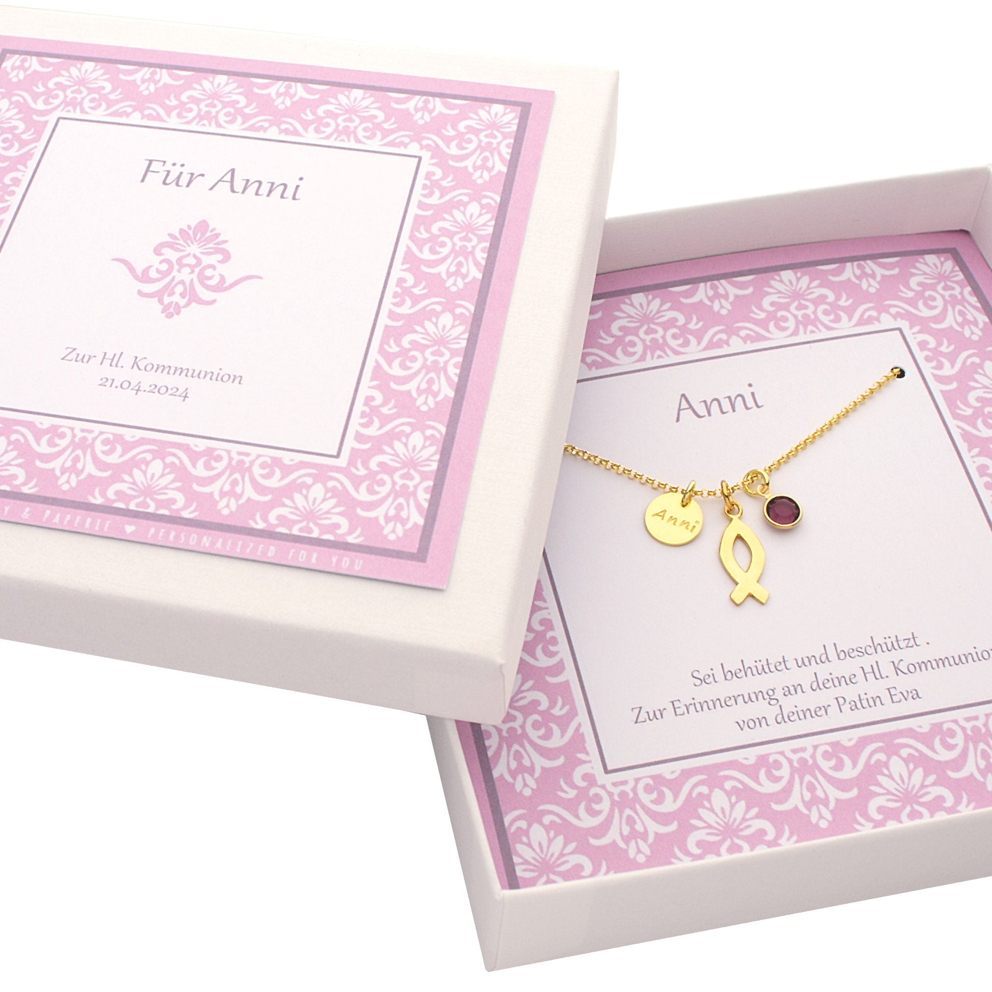 Taufkette aus vergoldetem 925 Silber von Bloomgart mit Fisch-Symbol, Namens-Gravur "Anni" und lila Februar-Stein, präsentiert in einer personalisierten Geschenkbox mit Taufspruch in flieder.