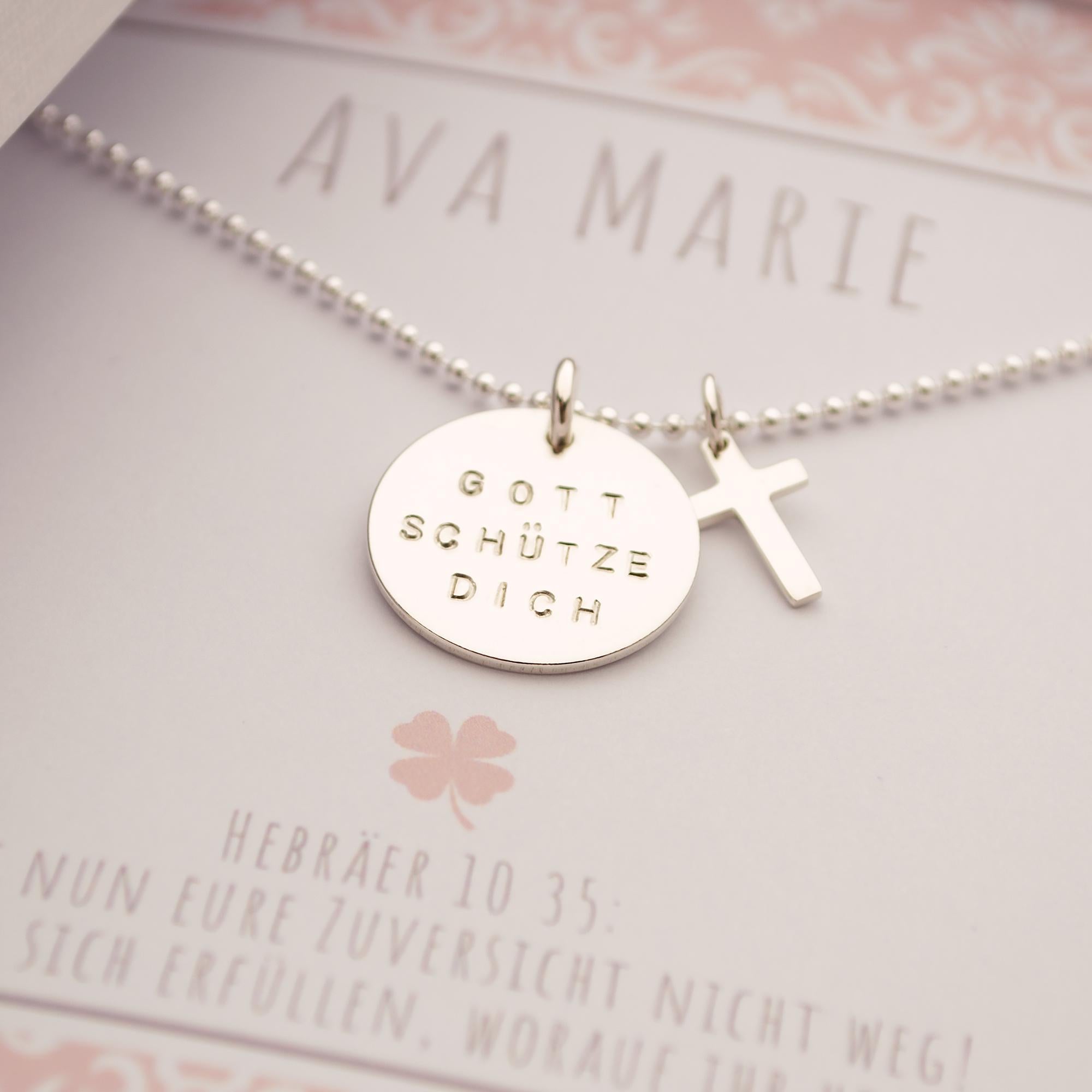 Makroansicht einer Sterlingsilber Kugelkette mit Gravurtaler 'Gott schütze dich" auf einer personalisierten Karte mit rosa-weißem Ornament-Muster, hier für Ava Maria und Taufspruch, Hebräer 10.35.