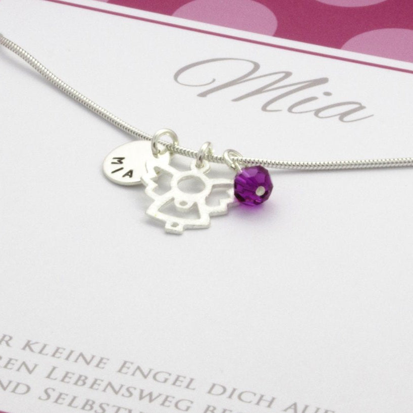Detailansicht einer Namenskette mit Gravur, Schutzengel und glücksstein-Kugel in einer pink-rosa gepunkteten Geschenkbox, personalisiert für 'Mia'.