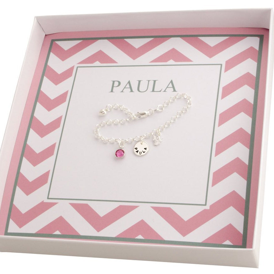 Innenansicht einer personalisierten Geschenkbox für 'Paula' mit rosa Zickzackmuster und Silberarmband mit Schutzengel, Name und Geburtsstein.