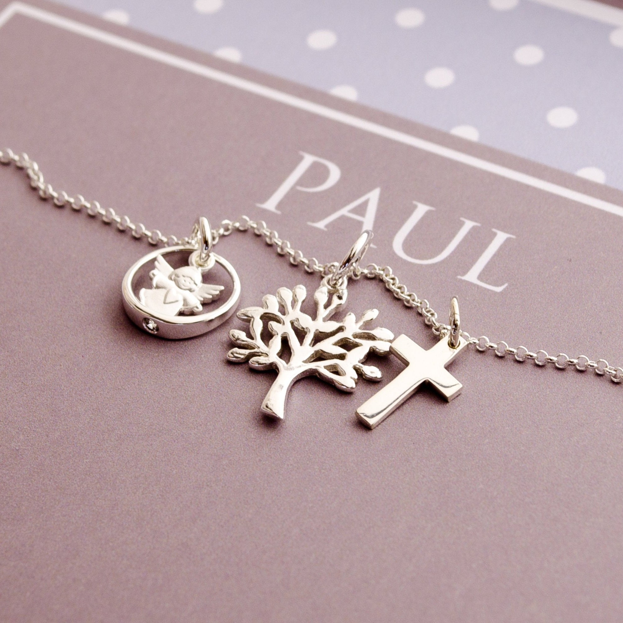 Detailansicht einer Taufkette für Jungen mit Kreuz, Lebensbaum und Schutzengel im Taufring an einer filigranen Erbskette aus 925 Sterling Silber.