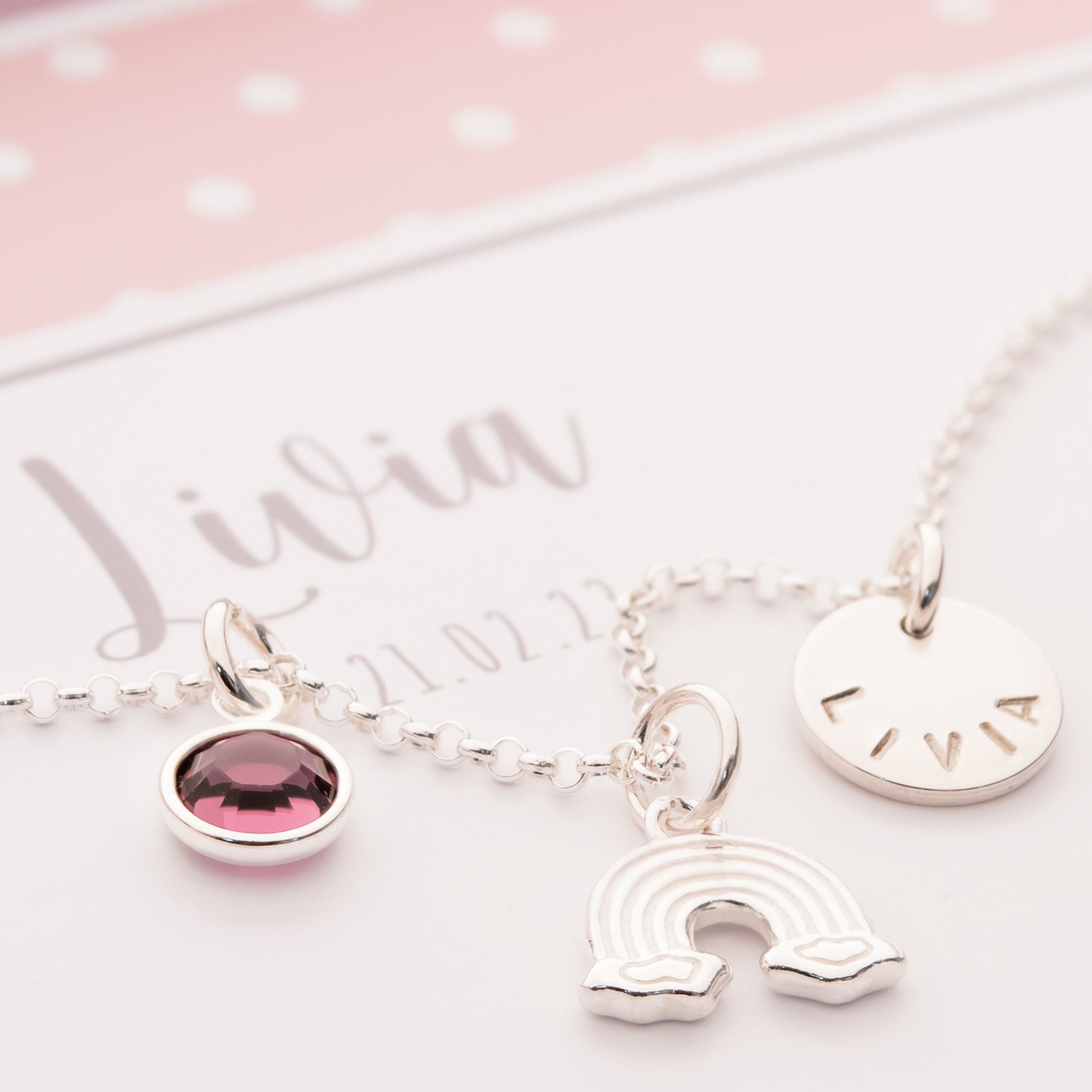 Personalisierte Regenbogen-Kette "Livia" aus 925 Silber mit Namensgravur und Geburtsstein, präsentiert in einer rosa-weißen Geschenkbox zur Taufe.