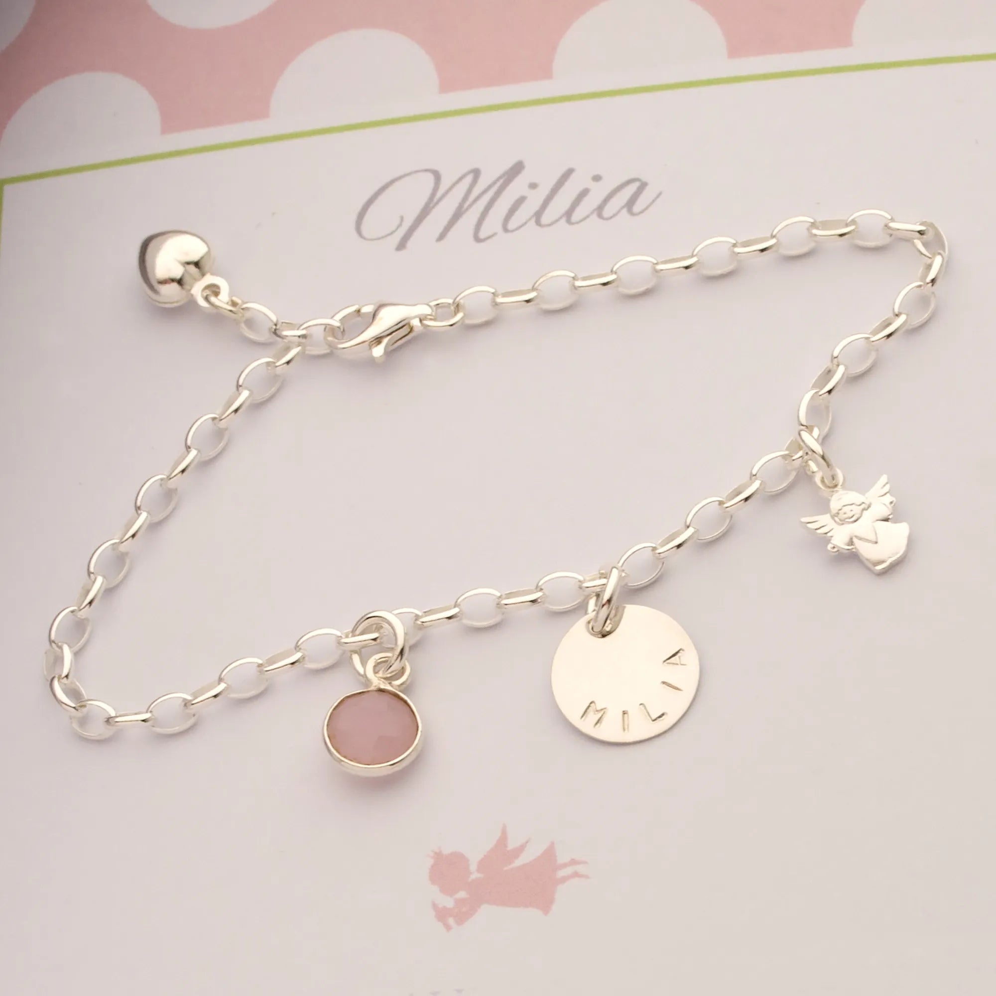 Ein Silberarmband mit den Anhängern: Rosenquarz, Namenstaler und kleinem Schutzengel. Das Armband kann variabel geschlossen werden und hat am Ende ein Herz.