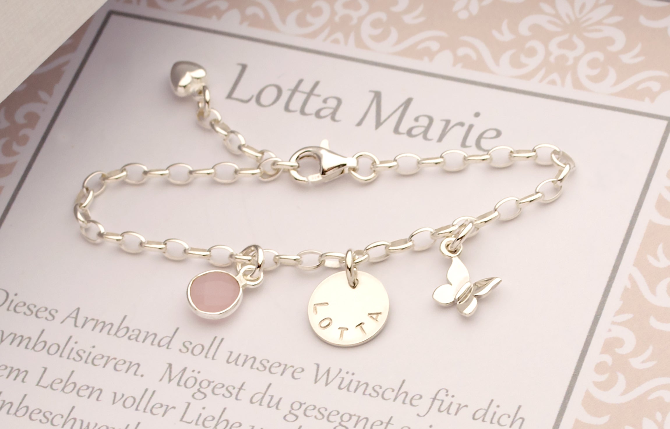 Mit Liebe handgemacht: Ein Silberarmband mit Schmetterling, Namensgravur und Rosenquarz, präsentiert in einer persönlichen Geschenkbox.