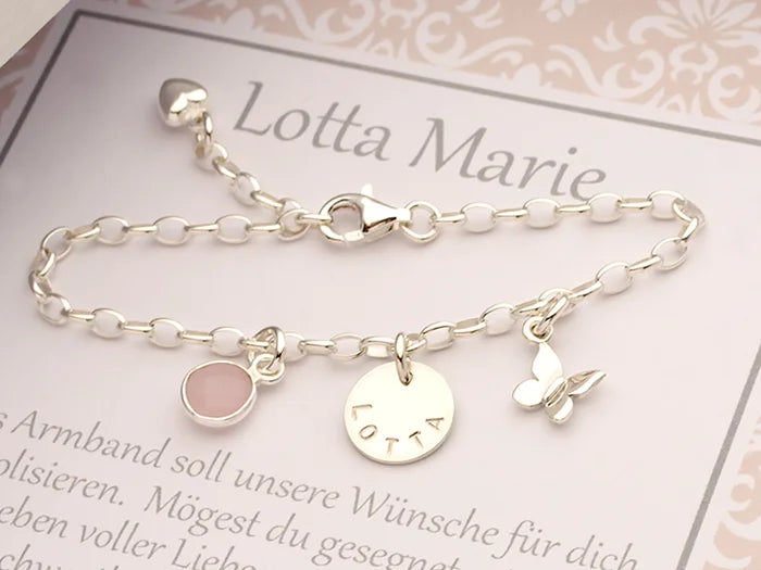 Mit Liebe handgemacht: Ein Silberarmband mit Schmetterling, Namensgravur und Rosenquarz, präsentiert in einer persönlichen Geschenkbox.