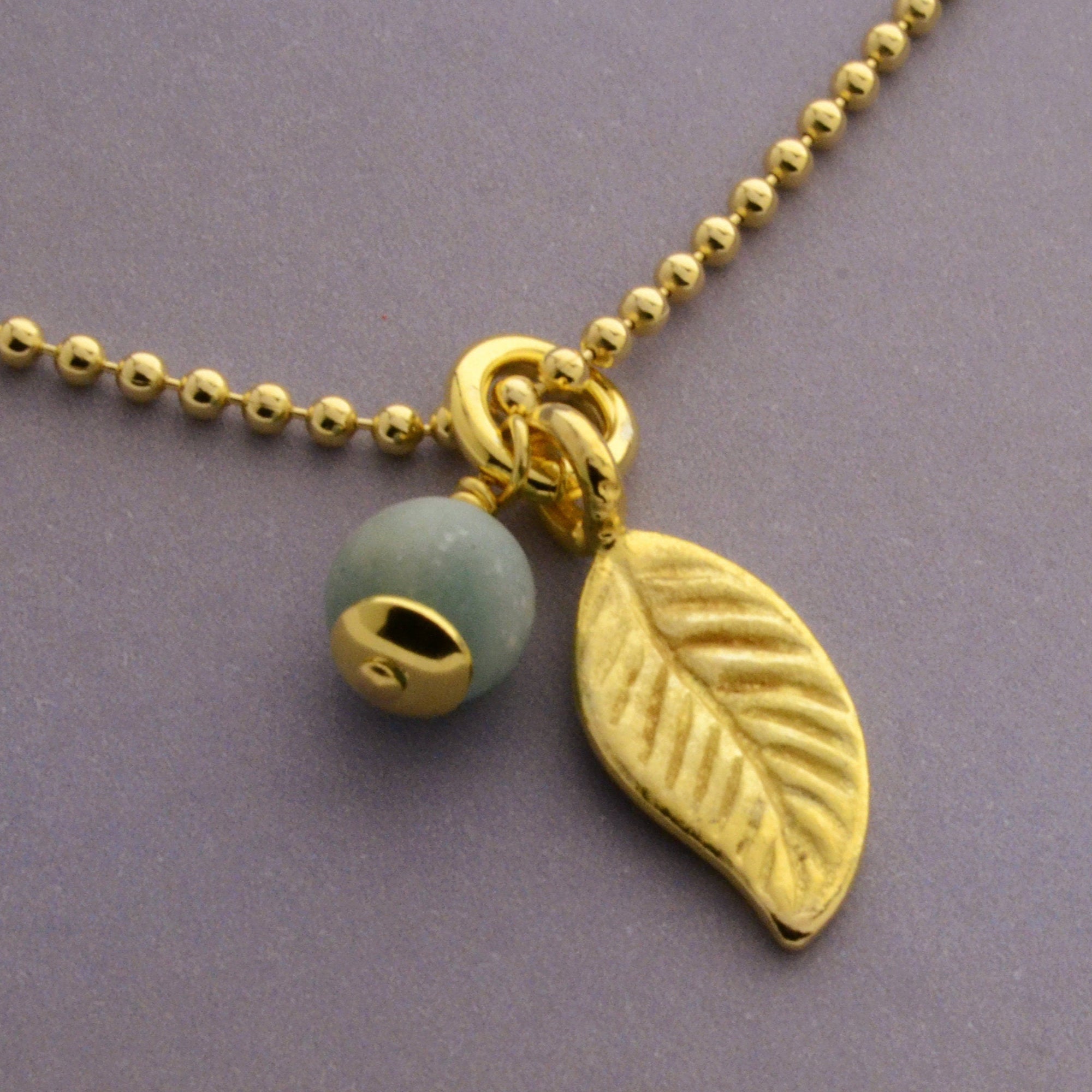 Nahaufnahme der filigranen Amazonit Halskette in Gold mit detailreichem Blatt-Anhänger von Bloomgart.