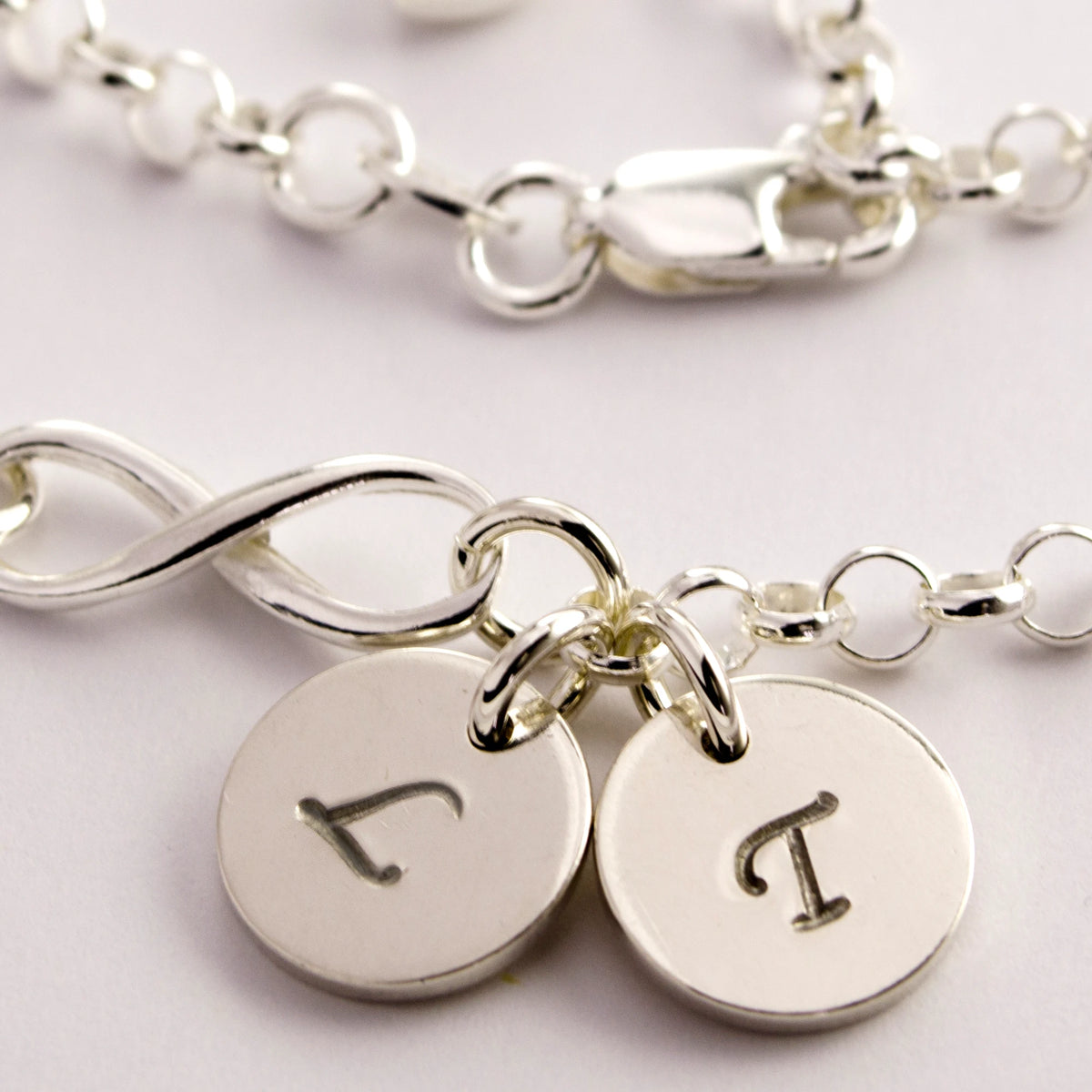 Detailansicht der Initialen auf den Plättchen des Infinity-Armbands.