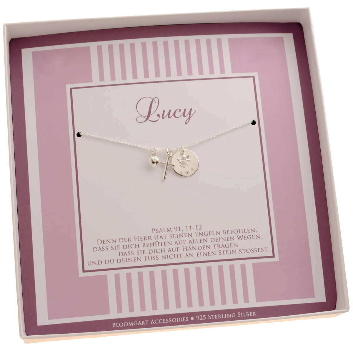 Innenansicht einer weiß-rosa Geschenkbox mit feiner Silberkette mit Engel über einem Namensplättchen, Kreuz und Herz-Anhänger, personalisiert für 'Lucy'. Unterhalb der Kette ist der Taufspruch: Psalm 91,11-12 gedruckt.