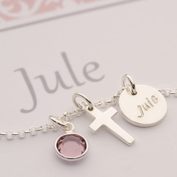 Detailaufnahme einer 925 Silberkette mit den Anhängern Juni Geburtsstein, Kreuz und ein Gravurtaler mit dem Namen 'Jule' auf einer personalisierten Geschenkbox.