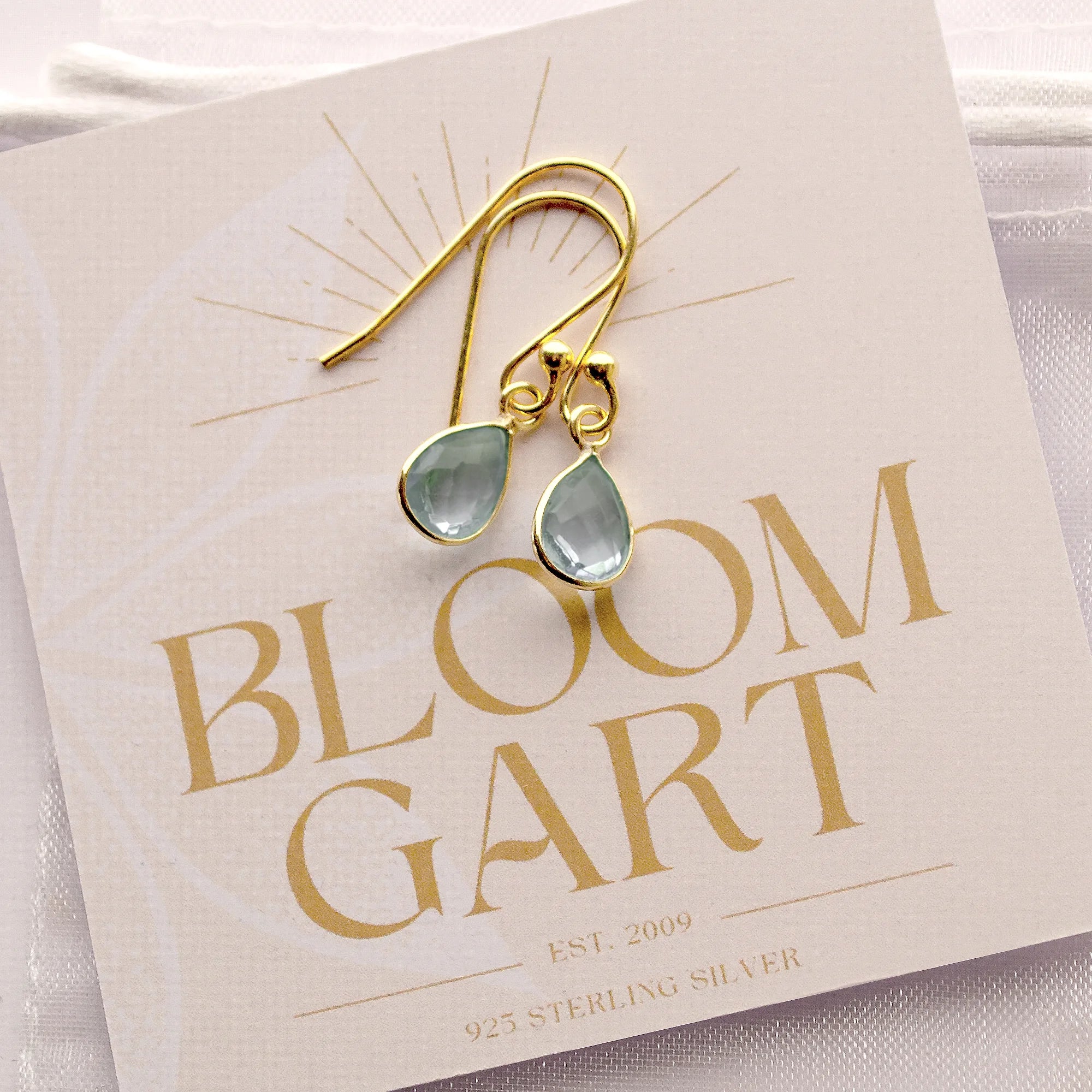 Zierliche Tropfen-Ohrringe mit Aqua Chalcedon und 925 Sterling Silber Fassung auf einer Bloomgart Geschenkkarte geschenkbereit befestigt.