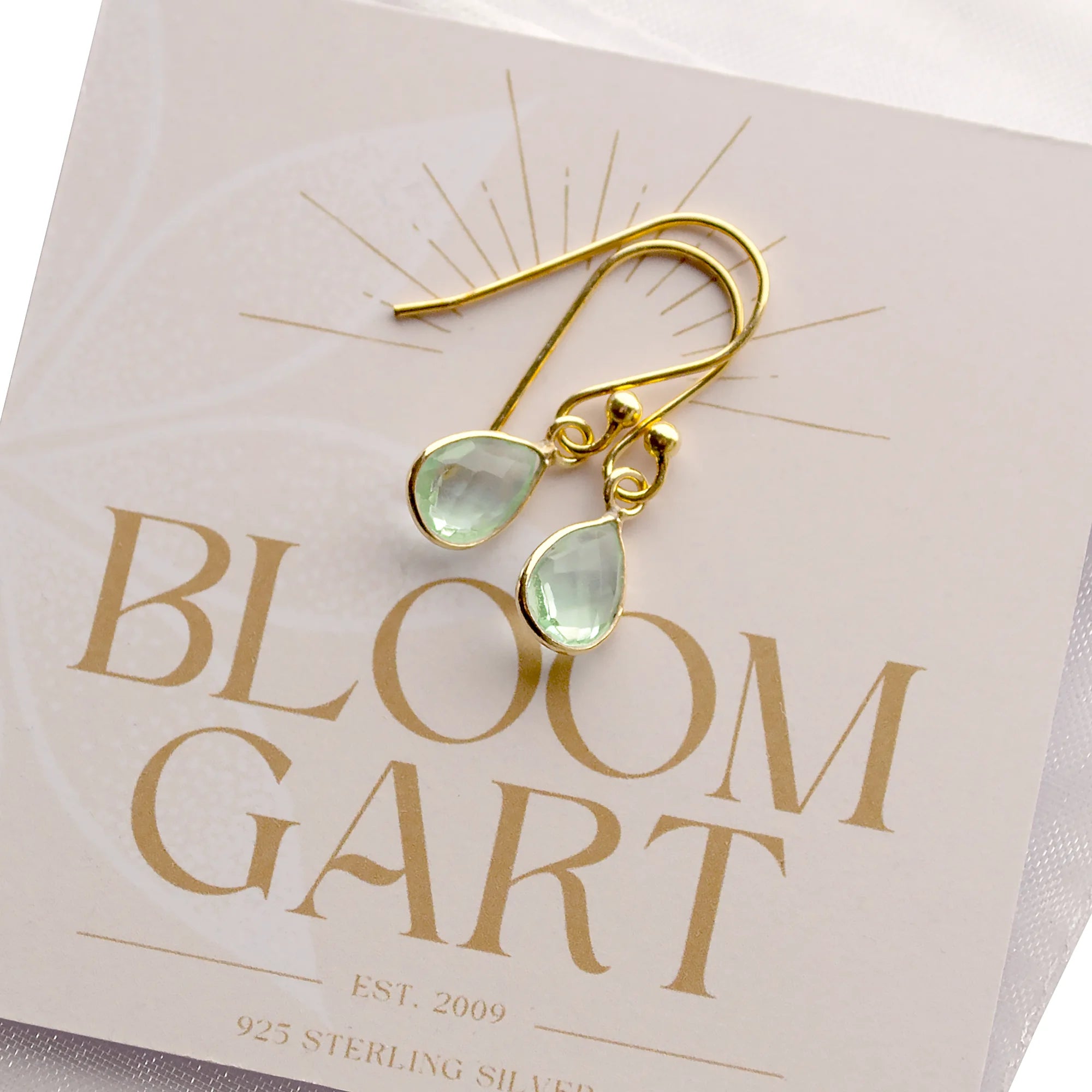 Edle Ohrringe mit grünen Amethyst-Tropfen in vergoldeter 925 Sterling Silber Fassung auf einer Karte von bloomgart.de