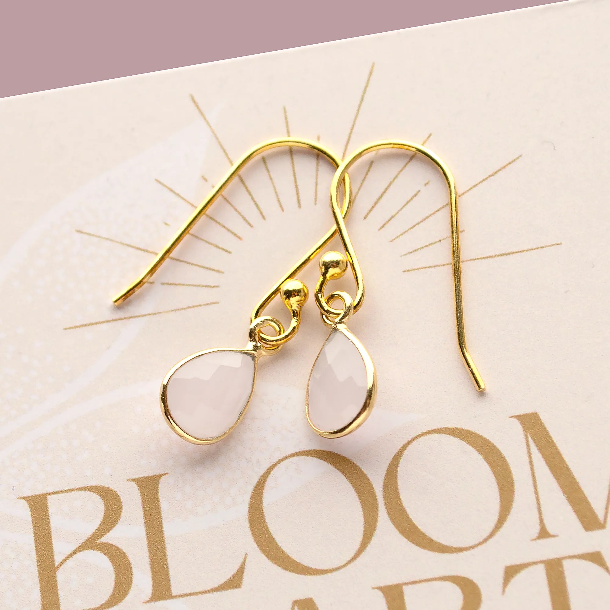 Filigrane Tropfen-Ohrringe mit Mondstein in vergoldeter 925 Sterling Silber Fassung auf einer Karte von bloomgart.de