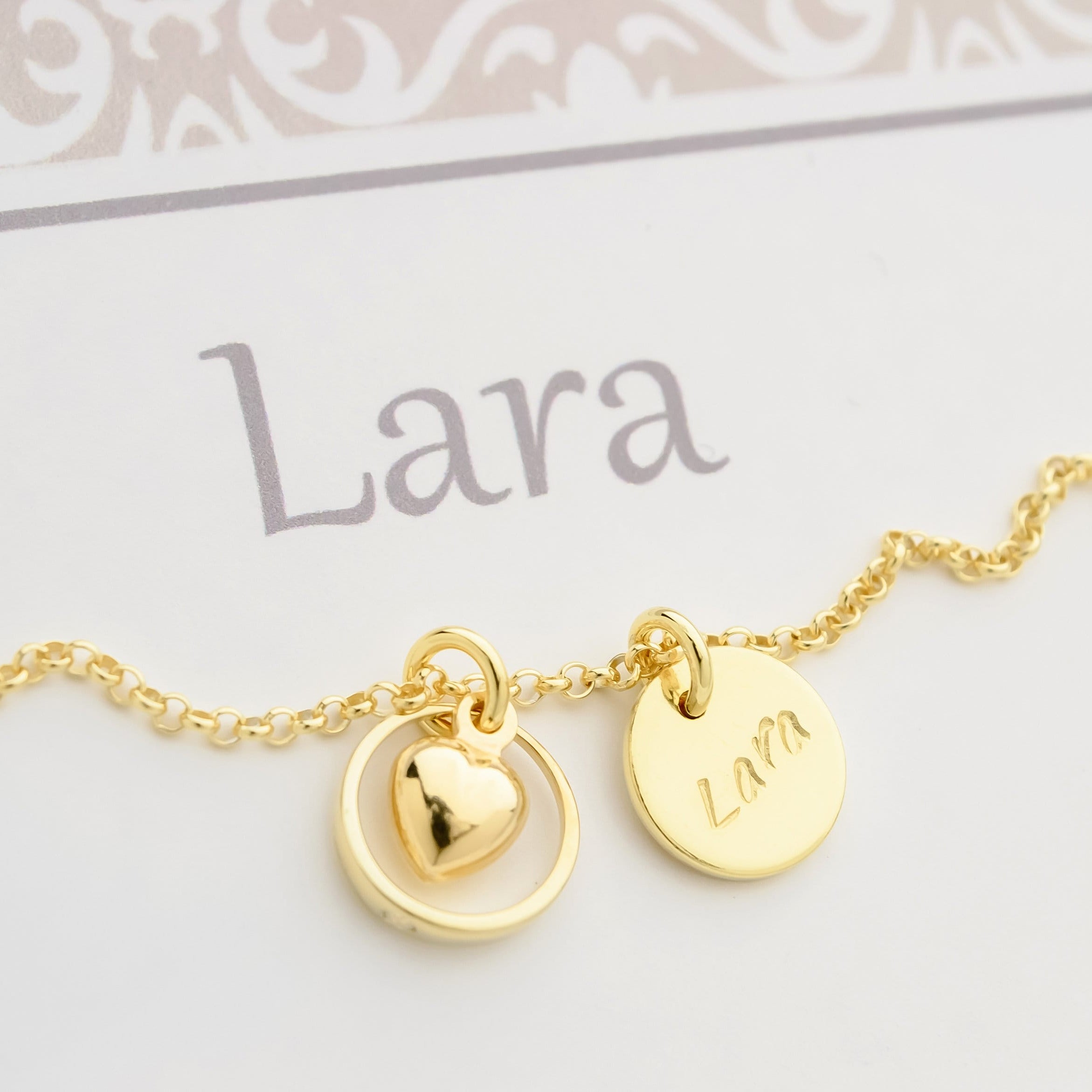 Personalisierte Halskette aus vergoldetem 925 Silber mit Namensgravur 'Lara' und einem Anhänger mit einem Herz in einem Taufring. Elegantes Tauf-Geschenk von Bloomgart.