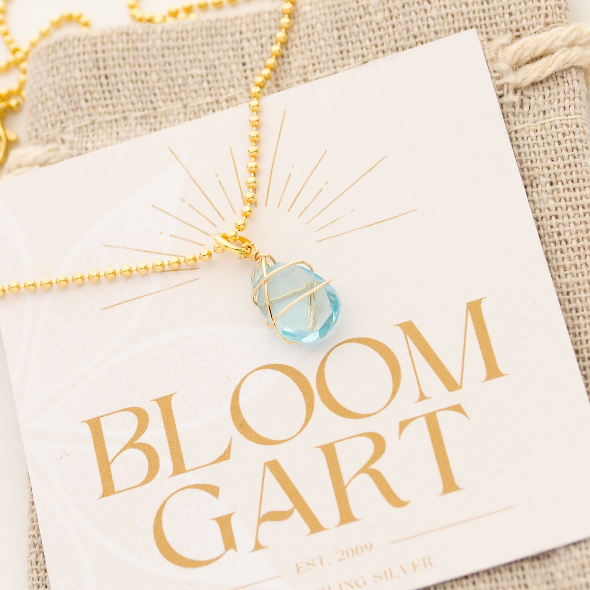 Detailansicht einer eleganten Goldketteim Boho Yogastil mit hellblauem Aqua Chalcedon und Gold-Umwickelung.