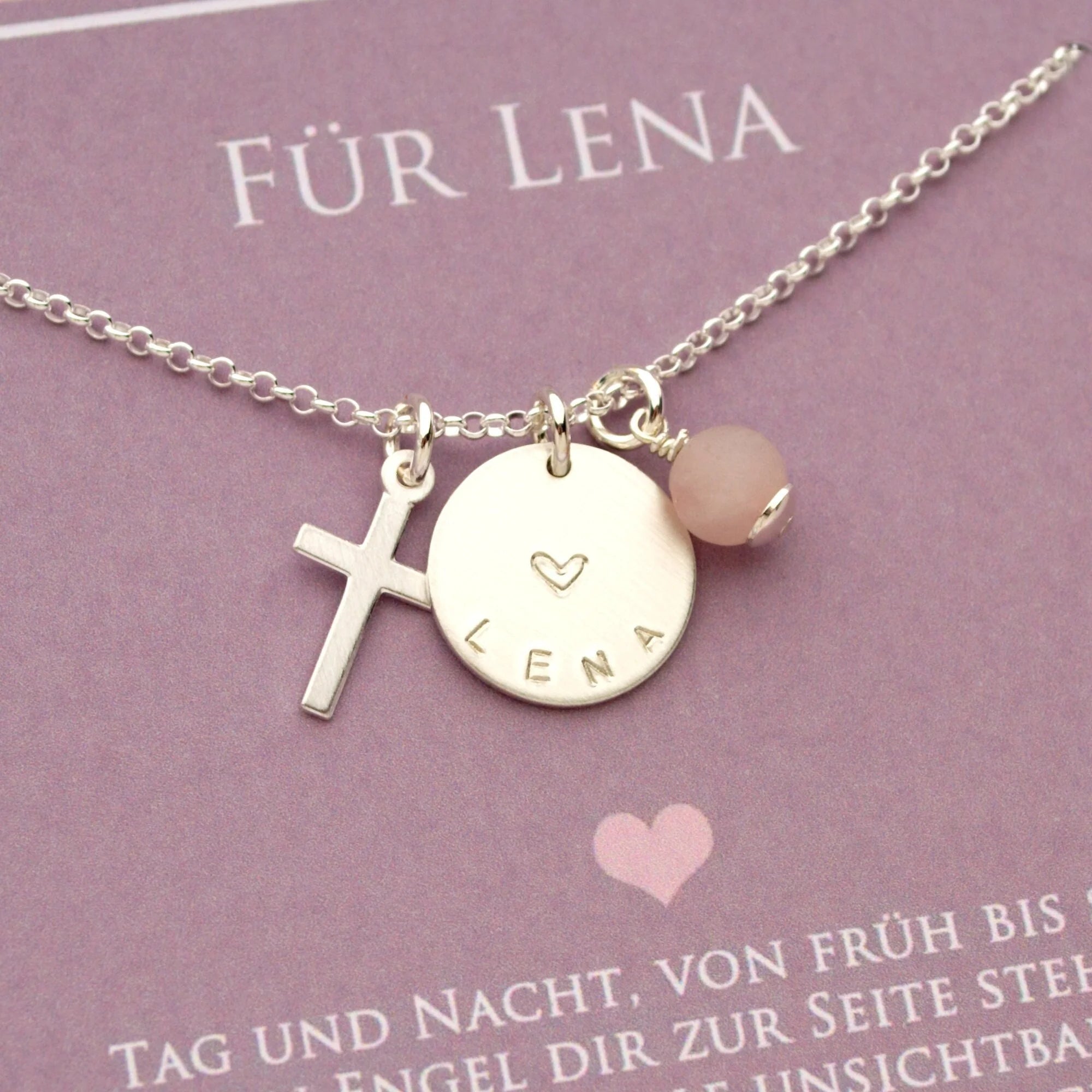 Nahaufnahme einer personalisierten 925 Silberkette mit Kreuz-Anhänger und einem Plättchen, das mit dem Namen 'Lena' und einem Herz graviert ist. Ein Geschenk zur Konfirmation oder Taufe.