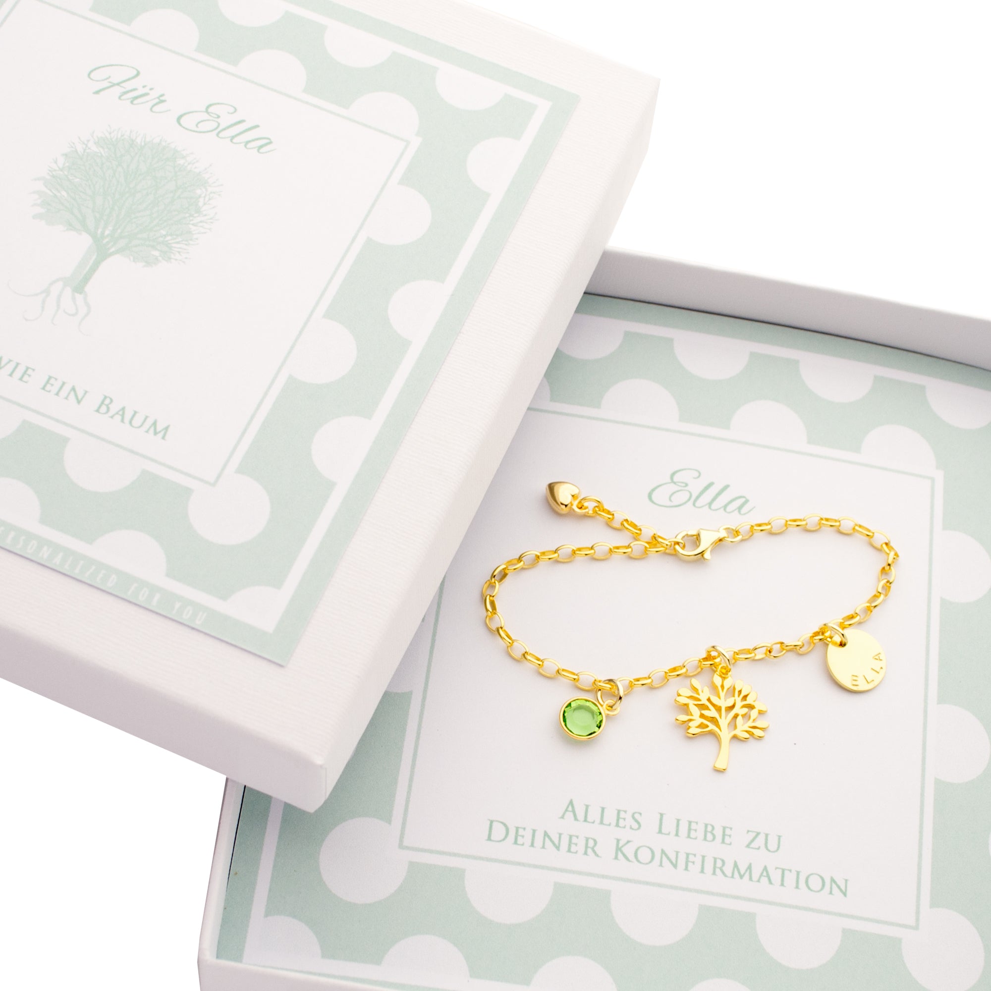 Personalisierte Geschenkbox zur Konfirmation von 'Ella' mit mint-weißem Punkte-Muster. In der Box liegt ein vergoldetes Gliederarmband mit Lebensbaum, grünem Geburtsstein und Namenstaler.