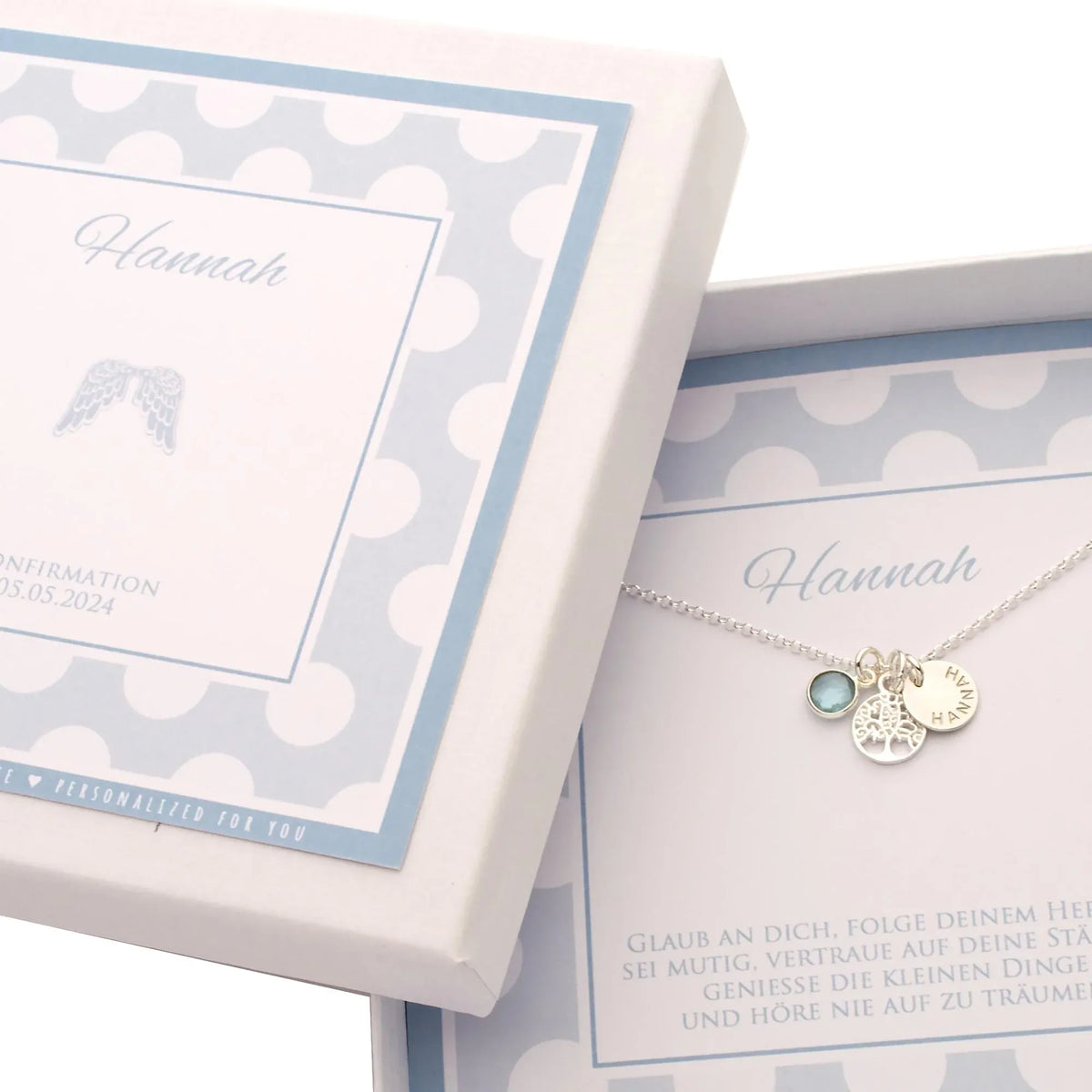 Personalisierte Lebensbaum-Kette aus 925 Silber mit Namensgravur und blauem Edelstein, präsentiert in einer Geschenkbox zur Konfirmation – Engelsflügel auf dem Cover.