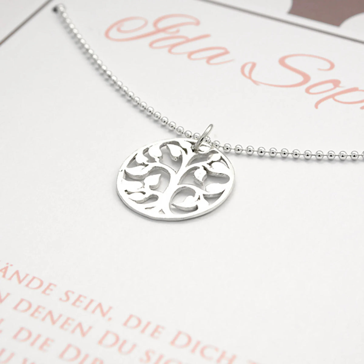 Detailansicht einer zarten Kugelkette mit Lebensbaum Anhänger aus 925 Silber auf einer personalisierten Karte in weiß, rosa, taupe.