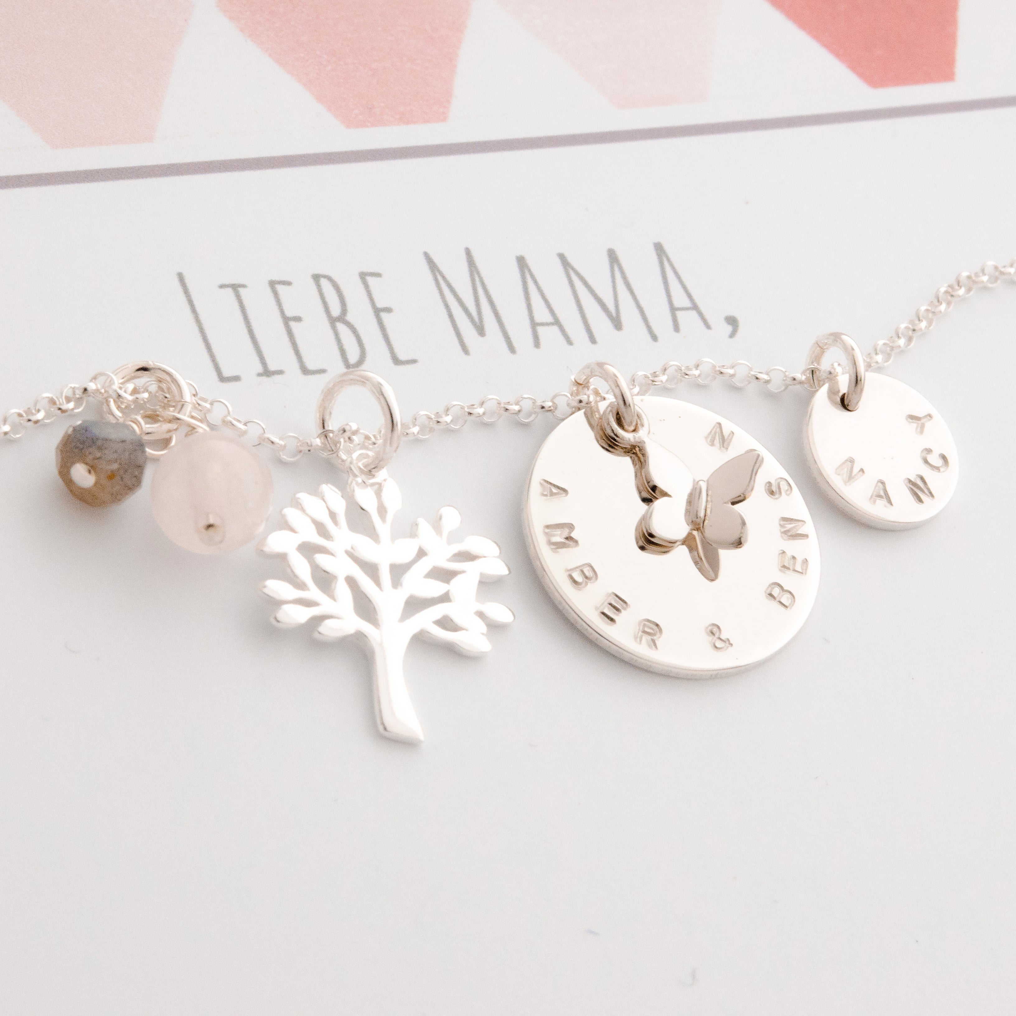 Nahaufnahme der personalisierten Lebensbaum Kette aus 925 Silber mit Namensgravur und Edelsteinen, auf einer Karte mit dem Text "LIEBE MAMA".