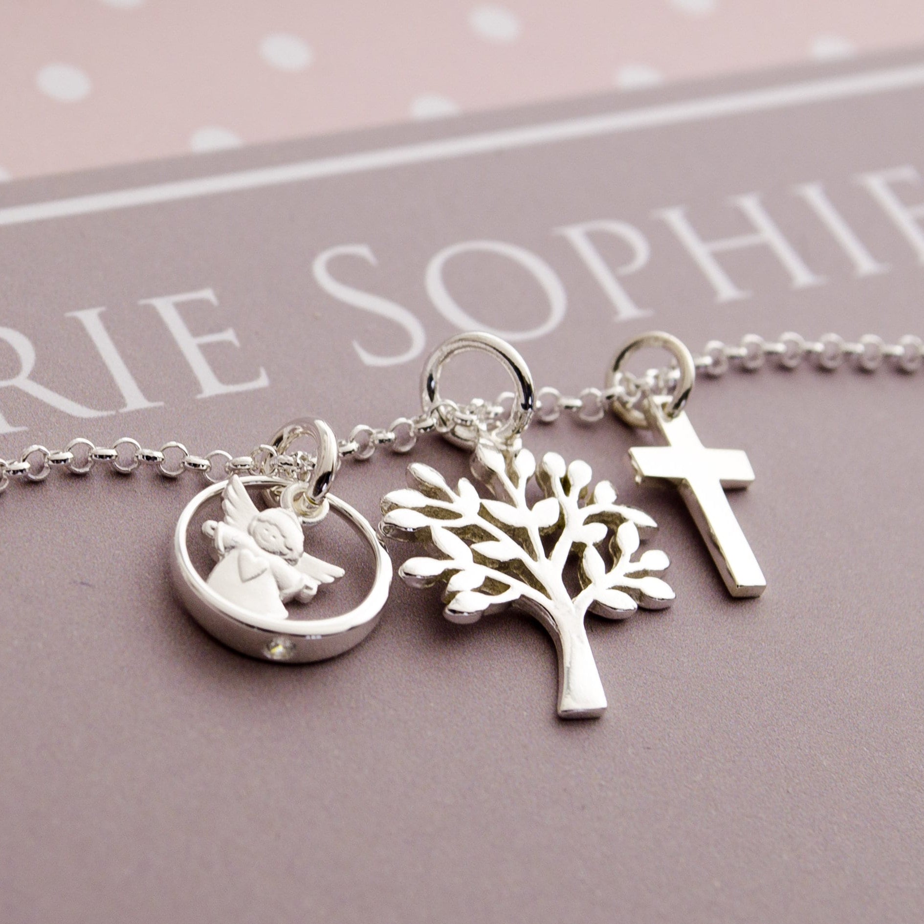 Detailansicht einer filigranen Gliederkette mit Lebensbuam, Kreuz und Schutzengel im Taufring. Ein ideales Geschenk zur Erinnerung an die Taufe, Kommunion oder Konfirmation.