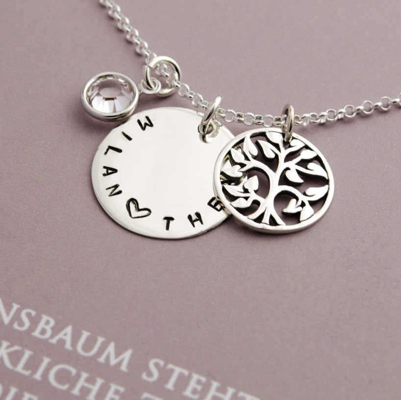 Makroansicht einer personalisierten Lebensbaum Kette aus 925 Sterling Silber mit 18 mm Gravurtaler, hier von Hand gestempelt mit 'MILAN Herz THEA', Geburtsstein April und rundem Lebensbaum-Anhänger.