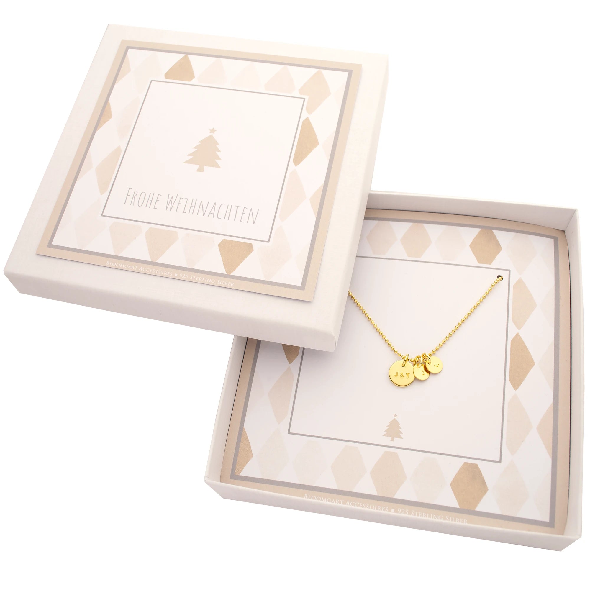 Komplettansicht einer weihnachtlichen Geschenkschachtel in beige-weiß mit goldener Kugelkette und drei Initial-Anhängern.