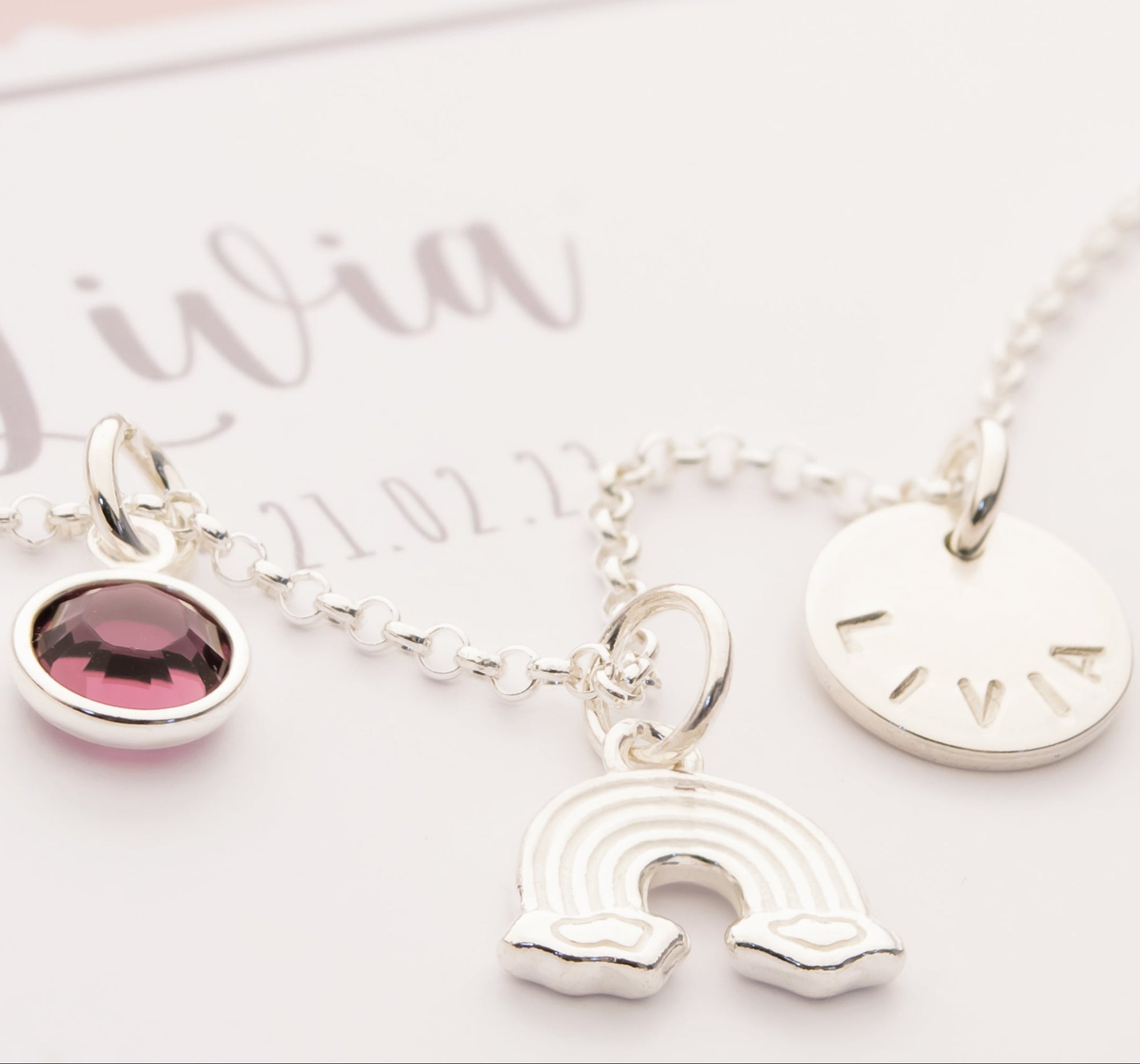 Personalisierte Regenbogen-Kette "Livia" aus 925 Silber mit Namensgravur und Geburtsstein, präsentiert in einer rosa-weißen Geschenkbox zur Taufe.