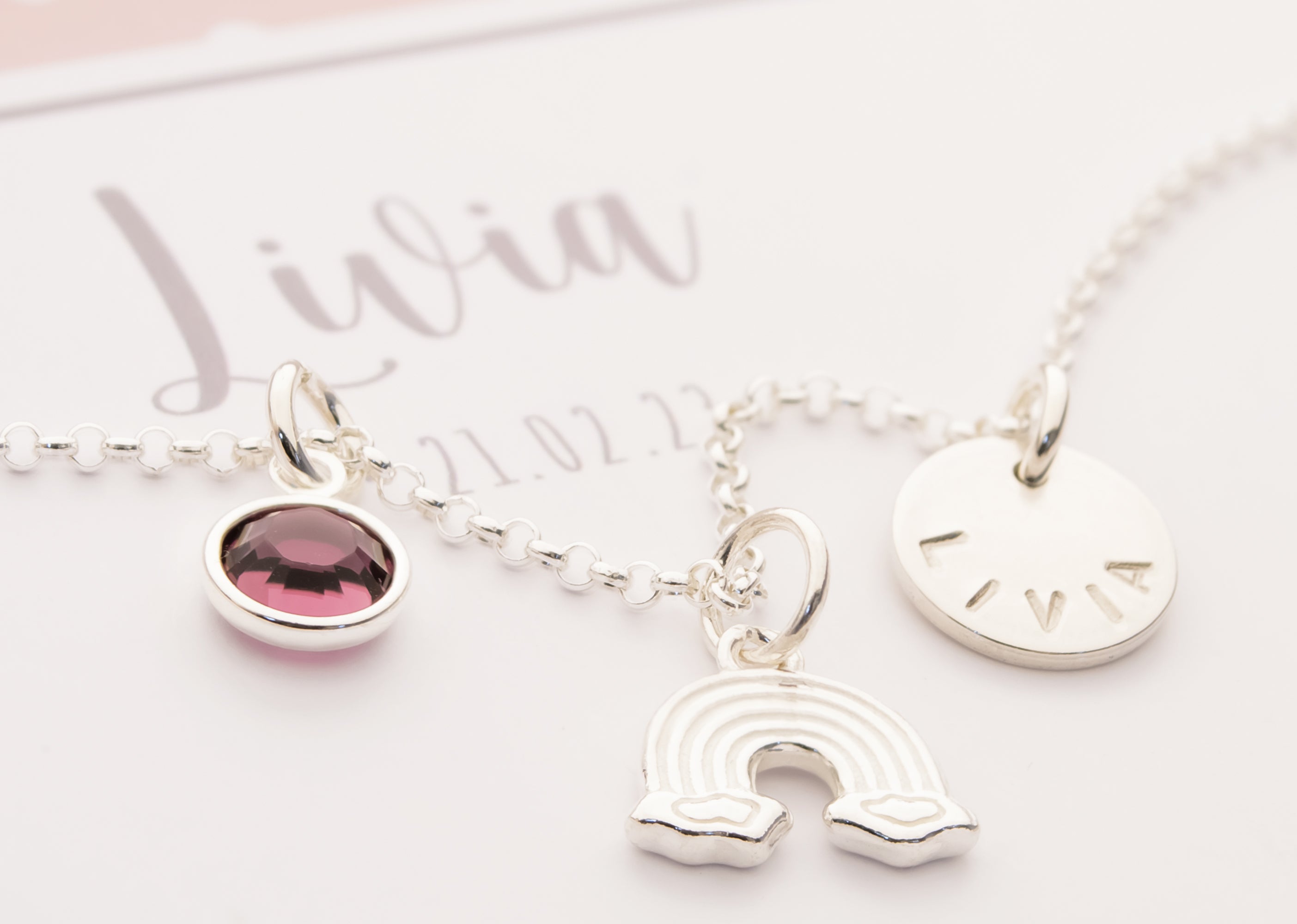 Personalisierte Regenbogen-Kette "Livia" aus 925 Silber mit Namensgravur und Geburtsstein, präsentiert in einer rosa-weißen Geschenkbox zur Taufe.