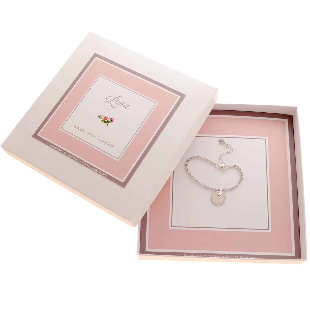 Personalisiertes Geschenk für Mädchen: in einer von Hand gefertigten Geschenkbox in rosa-weiß liegt ein längenverstellbares Namensarmband aus 925 Silber mit Herz und Kleeblatt Anhängern.