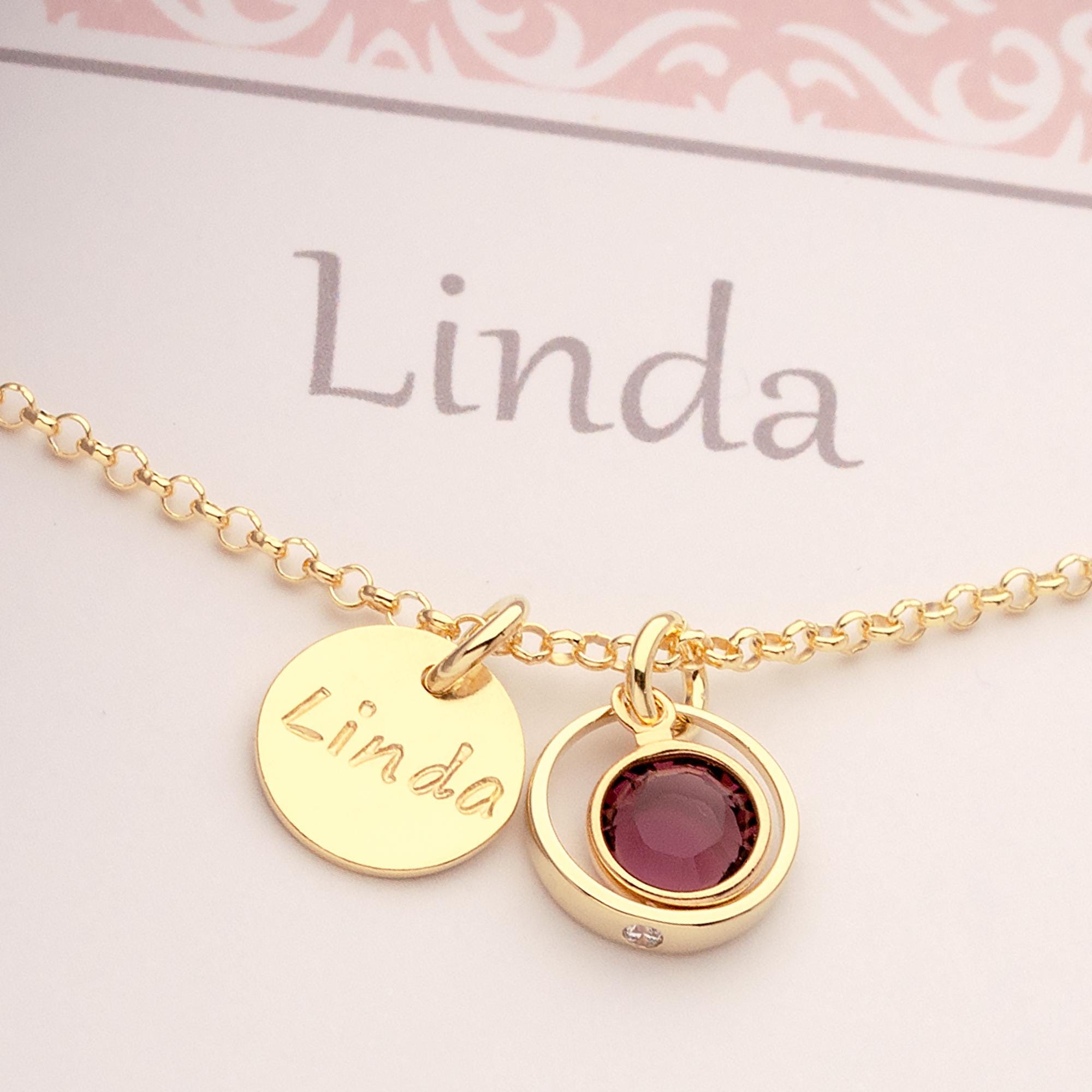 Nahaufnahme einer Gold Taufkette "Linda" mit Namensgravur Taler und lila Amethyst-Geburtsstein in einem zierlichen Taufring mit weißem Zirkon.
