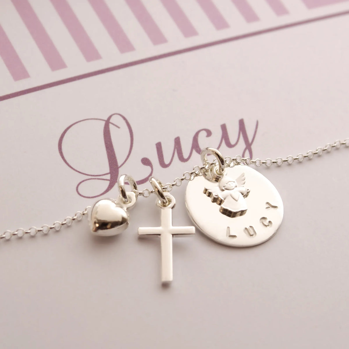 Detailansicht einer Namenskette aus 925 Sterling Silber mit Schutzengel, Kreuz und Herz-, handgestempelt für 'Lucy'.