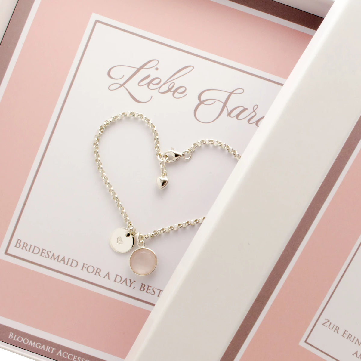 Personalisiertes Geschenk für deine Trauzeugin: ein 925 Silberarmband mit rundem Rosenquarz in Silber gefasst und einem rundem Silberplättchen mit handgestempeltem Herz, präsentiert in einer personalisierten weiß-rosa Geschenkbox.