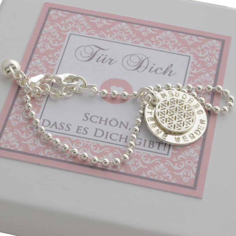 Detailansicht des Silberarmbandes mit Wunschgravur, hier "Sterne werden geboren" mit Lebensblume, präsentiert in einer kleinen rosafarbenen Bloomgart Geschenkbox.